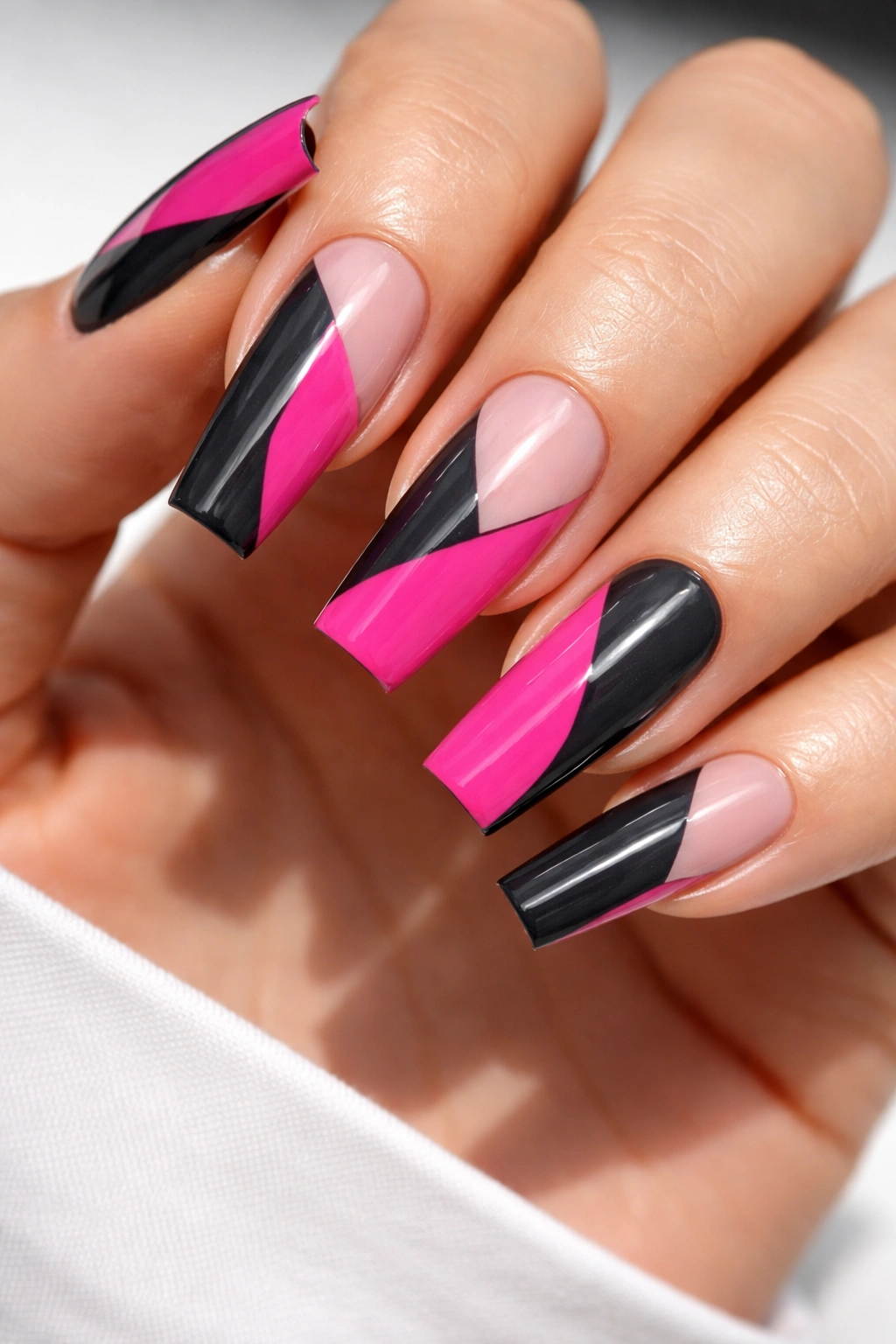 Close-up of hot pink and charcoal color-block coffin nails with bold geometric panels and glossy finish