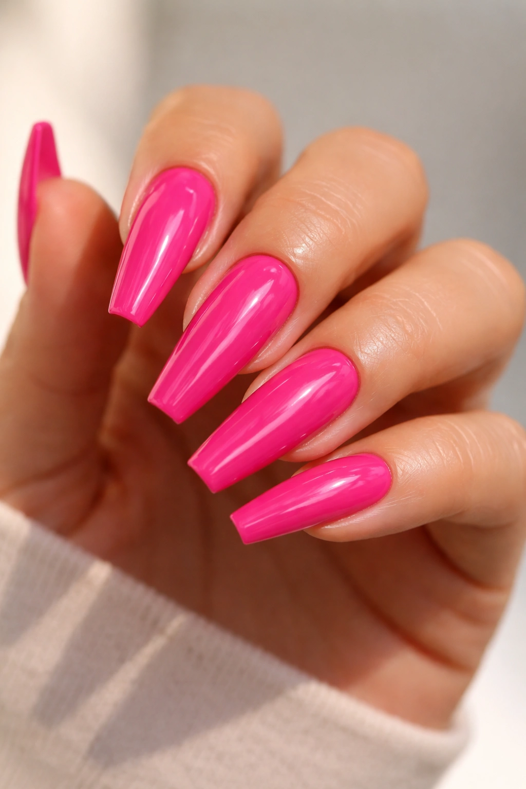 Close-up of hot pink gloss coffin nails with glassy top coat
