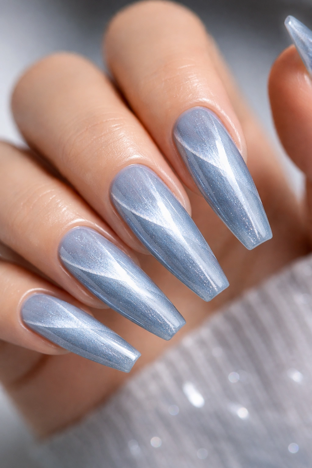 Close-up of ice blue cat-eye coffin nails with diagonal stripe