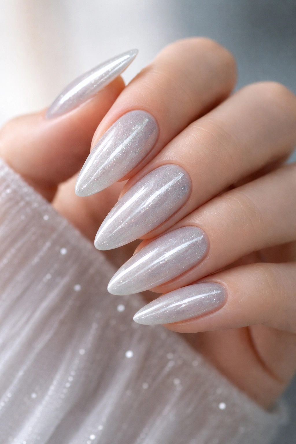 Close-up of ice queen cat eye almond nails with pale icy base and silver shimmer