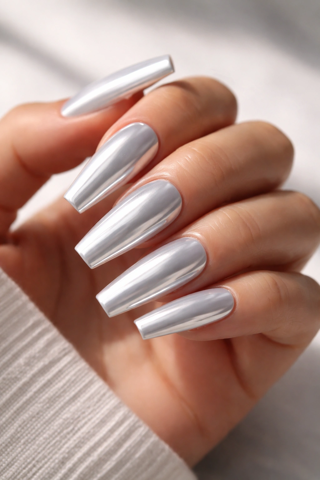 Close-up of icy mirror white chrome coffin nails with ultra-reflective surface