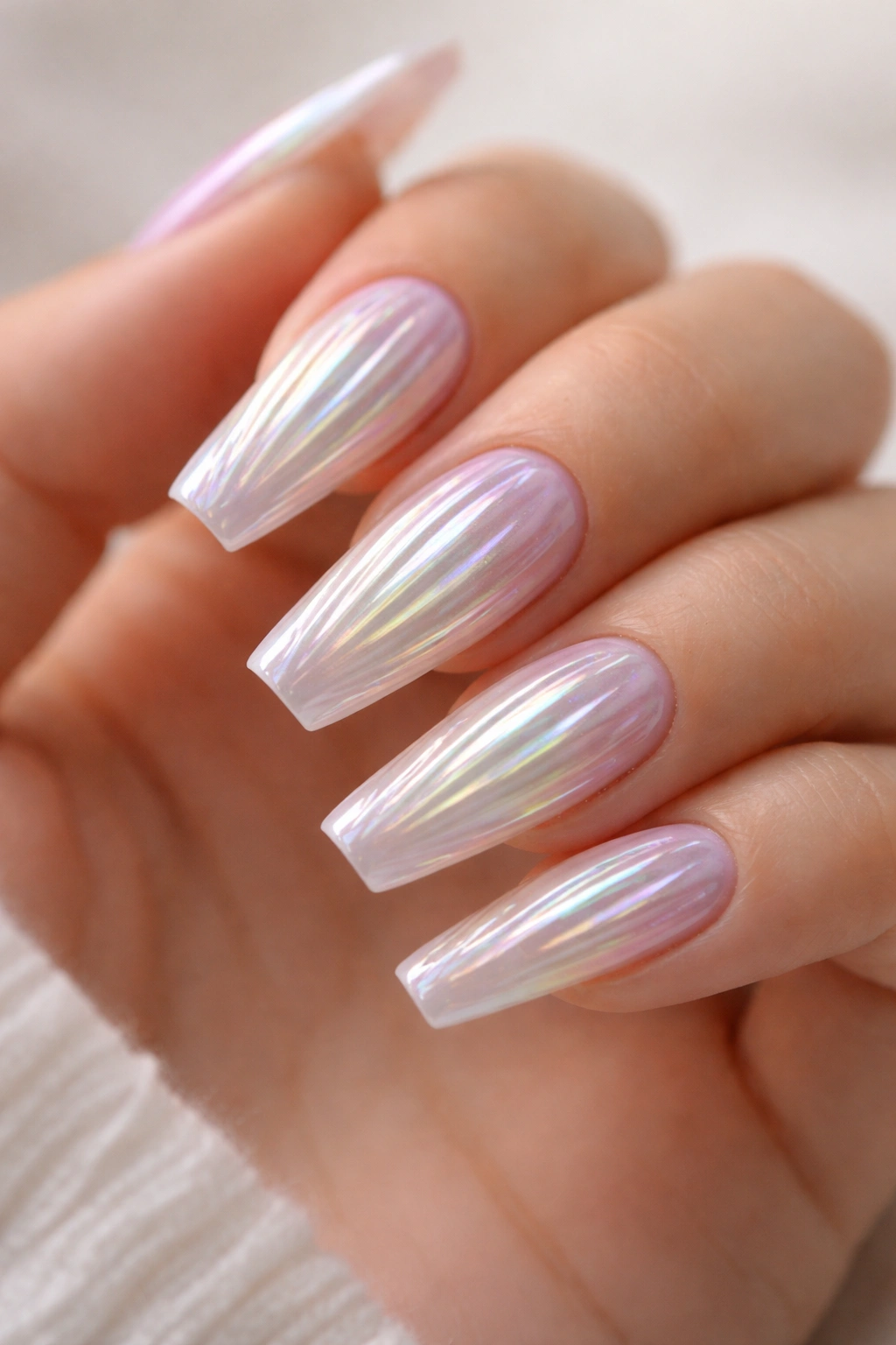 Coffin nails with pale base and iridescent seashell shimmer under soft light