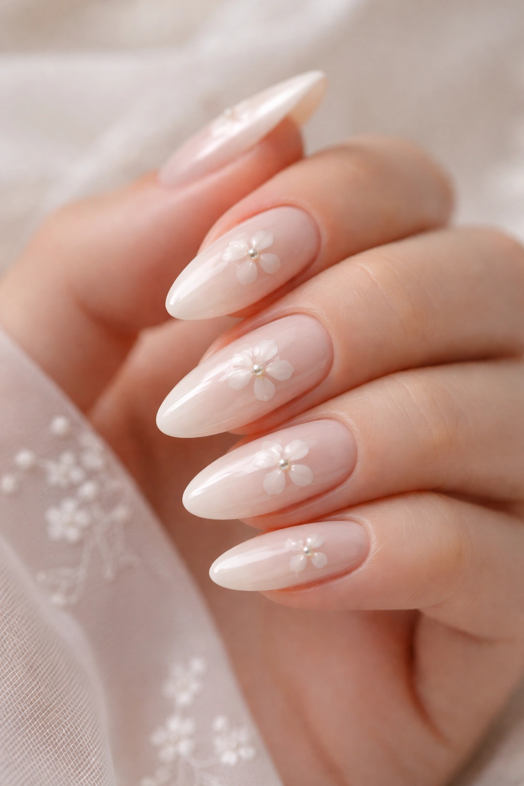 Close-up of ivory almond nails with pearl centers and delicate petals