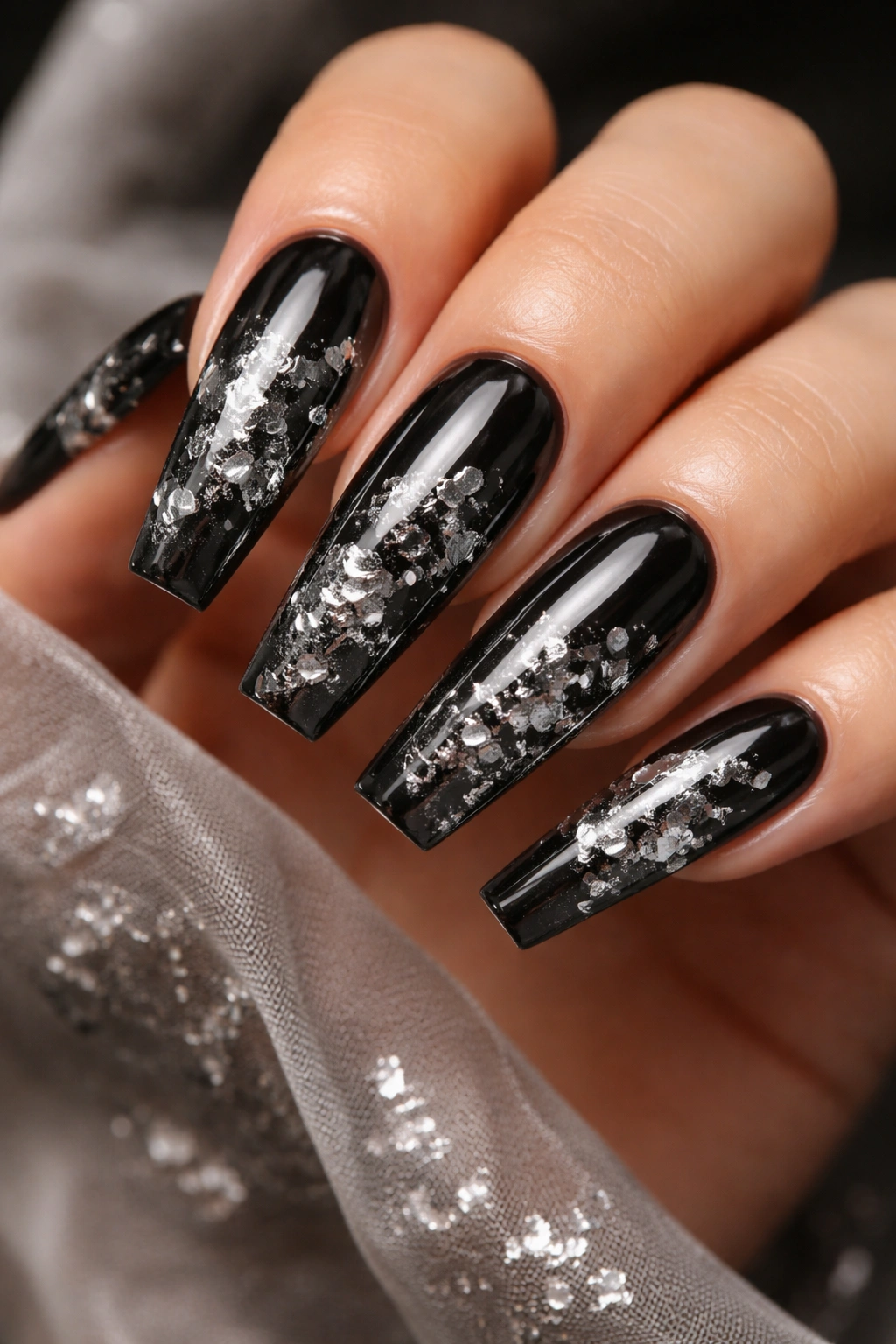 Close-up of translucent black jelly coffin nails with embedded silver foil