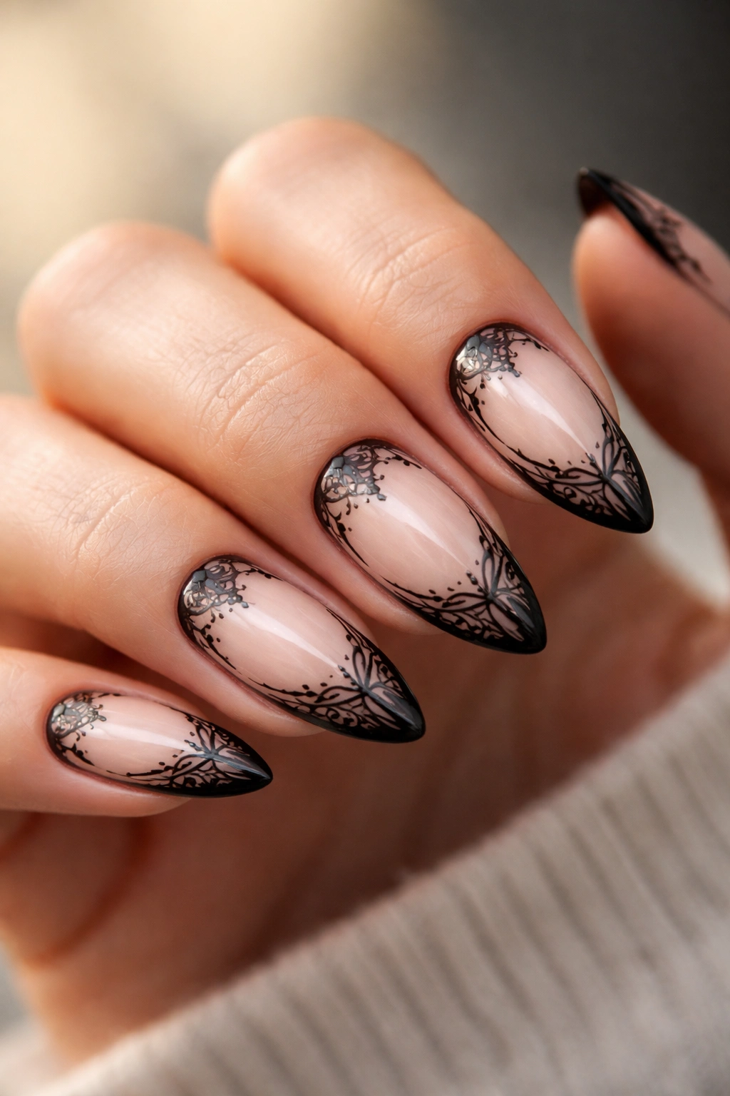 Almond nails with delicate lace-inspired black line art on a nude base
