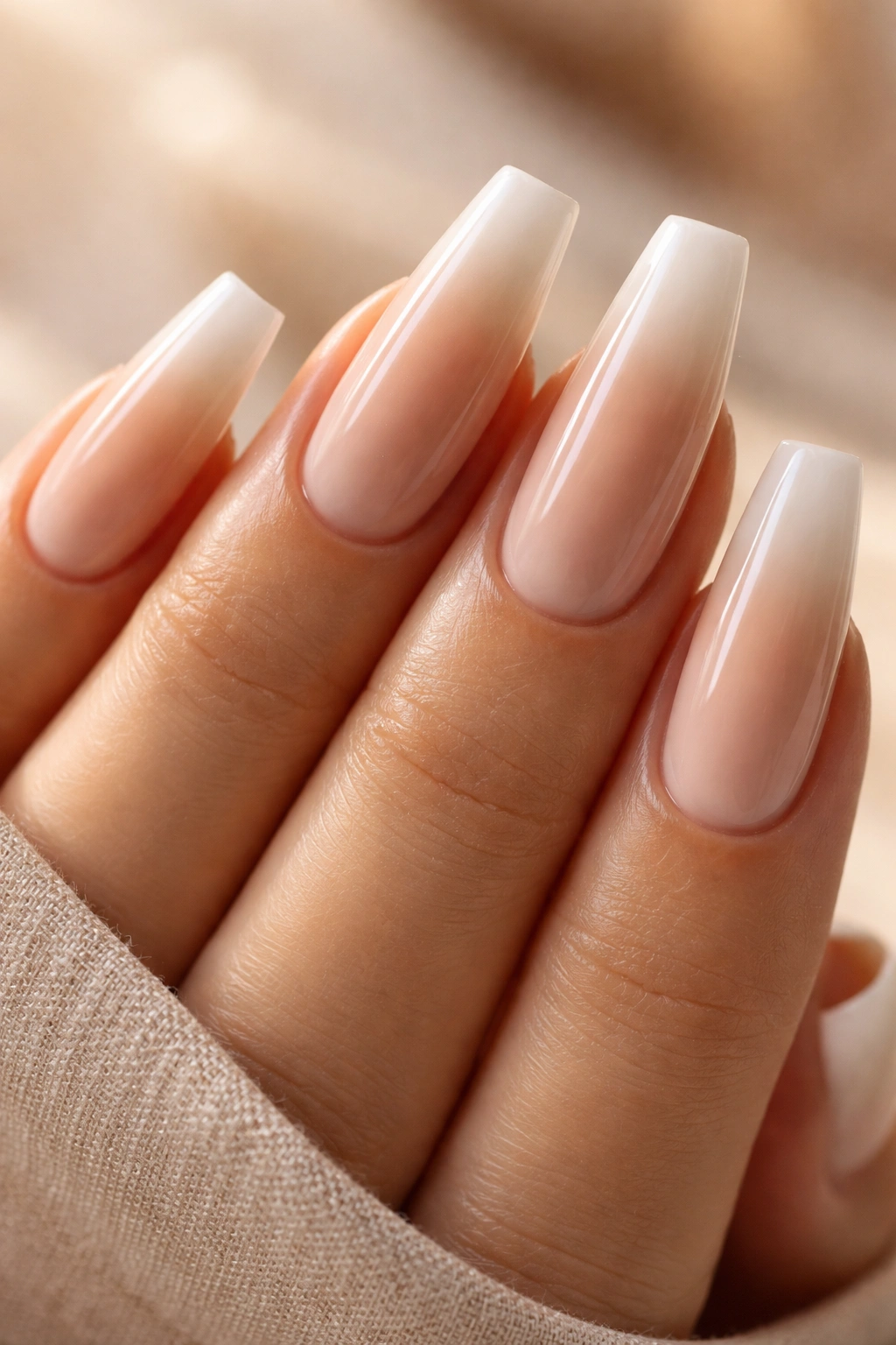 Close-up of latte beige coffin nails with a sheer white halo