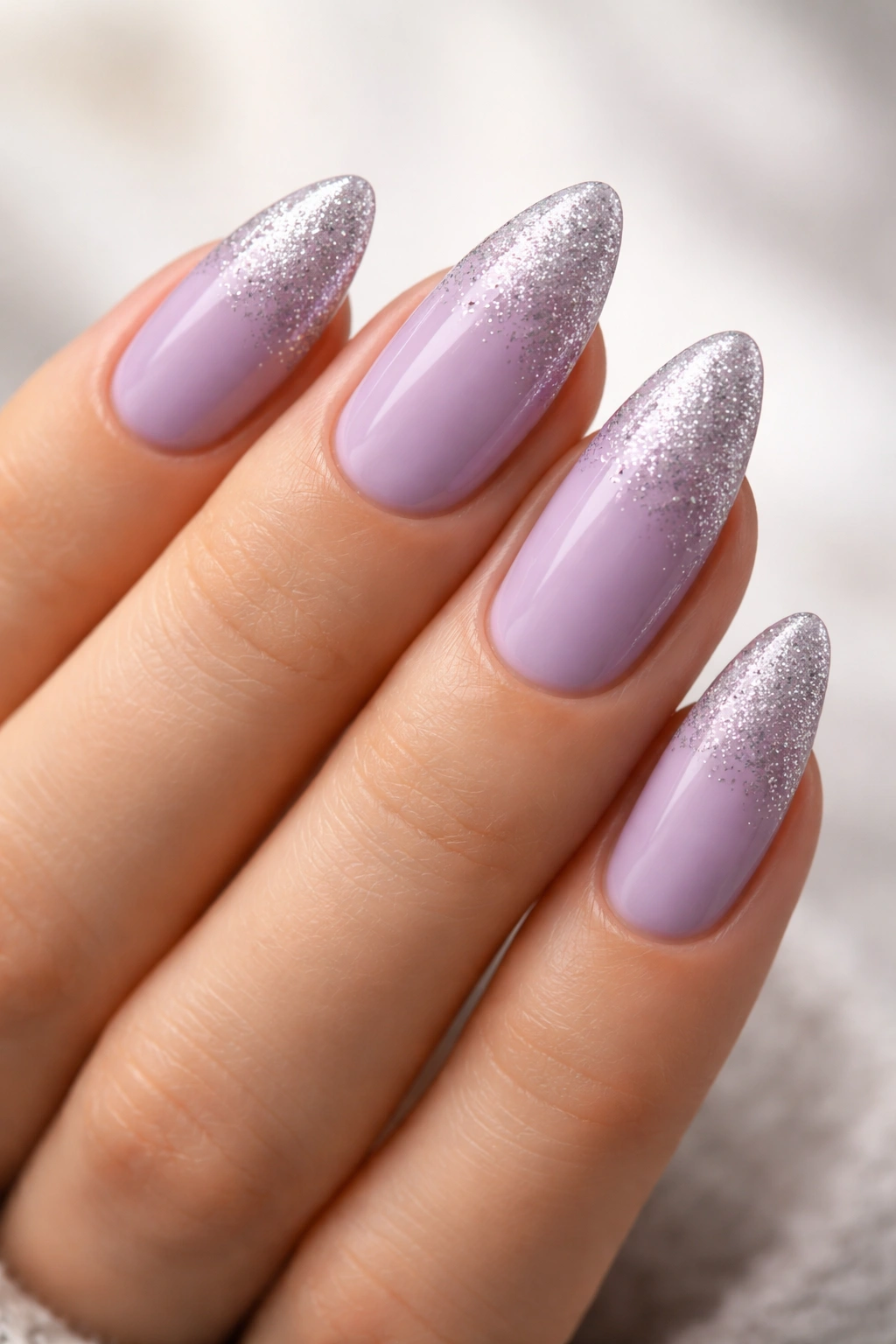 Close-up of lavender almond nails with a subtle silver glitter fade