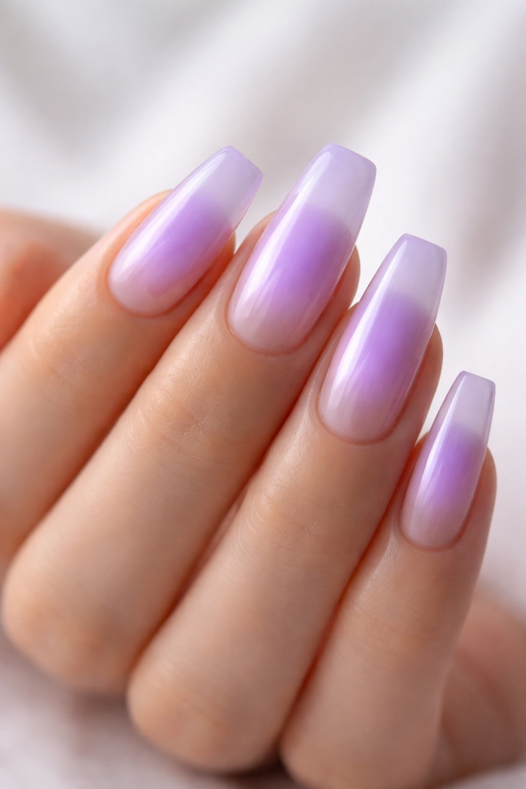 Close-up of coffin nails with a lavender aura gradient and sheer base