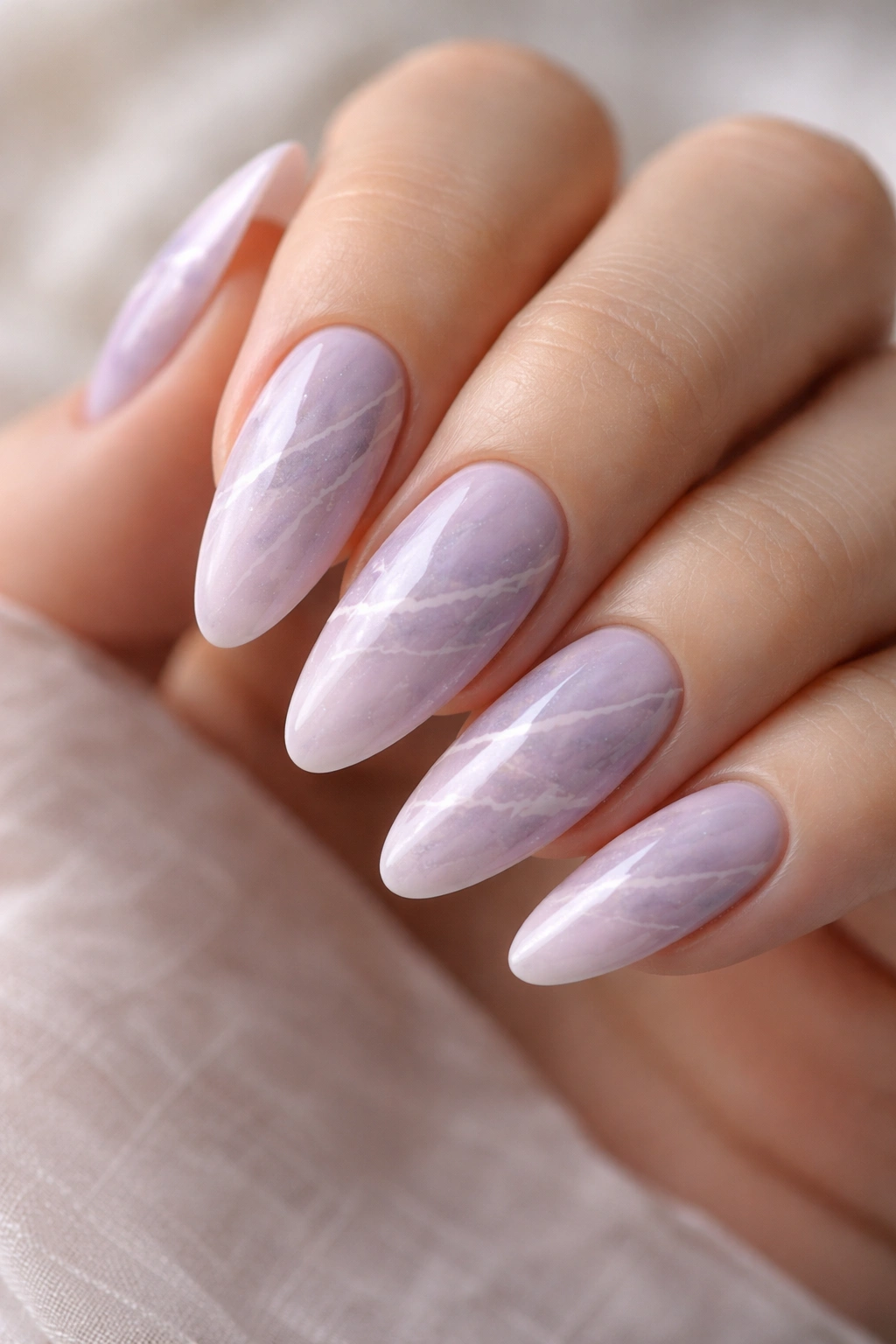 Close-up of lavender marble nails on almond shape with white veining
