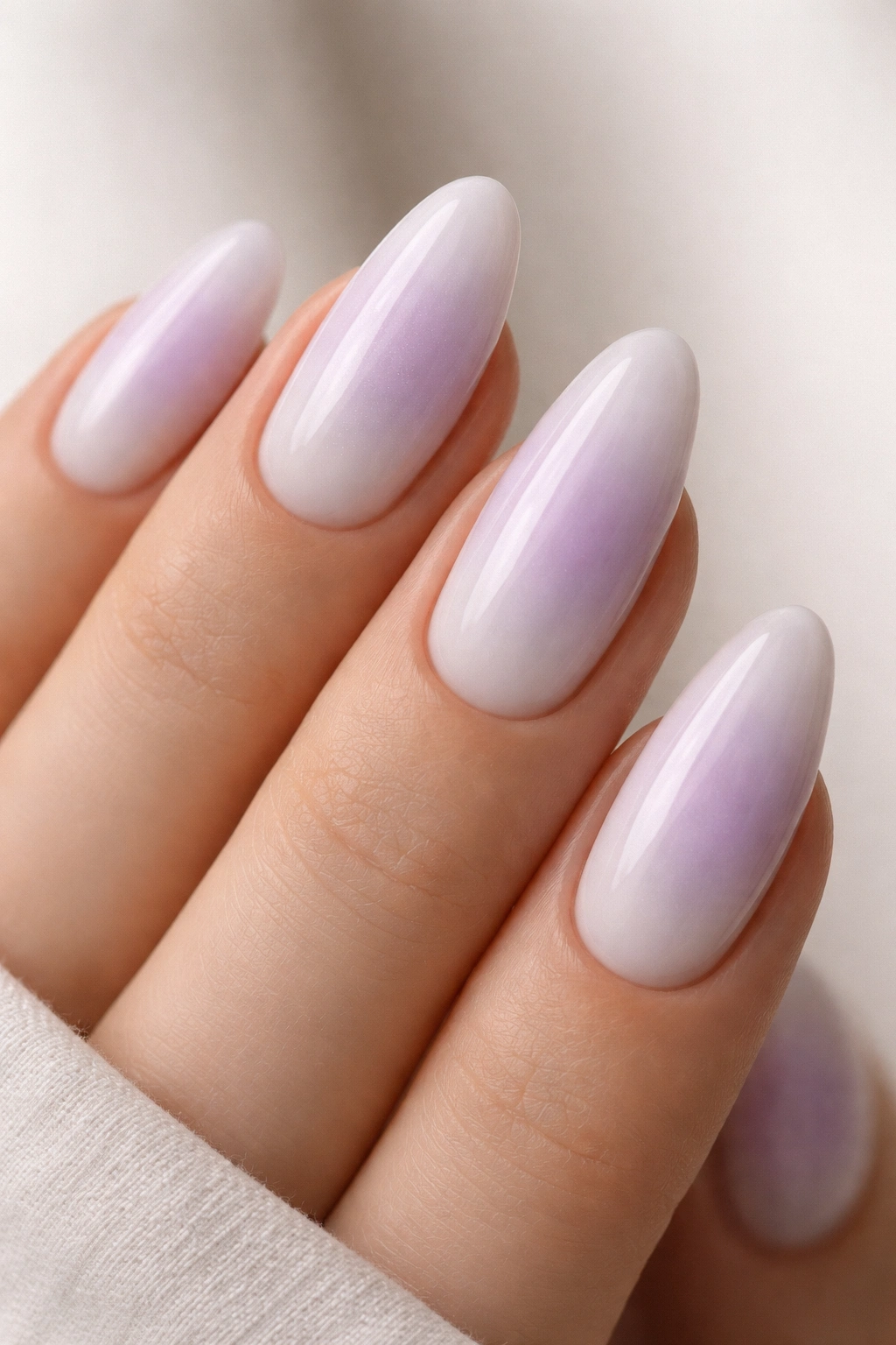 Almond nails with lavender milk fade featuring a soft gray-centered gradient on a white base