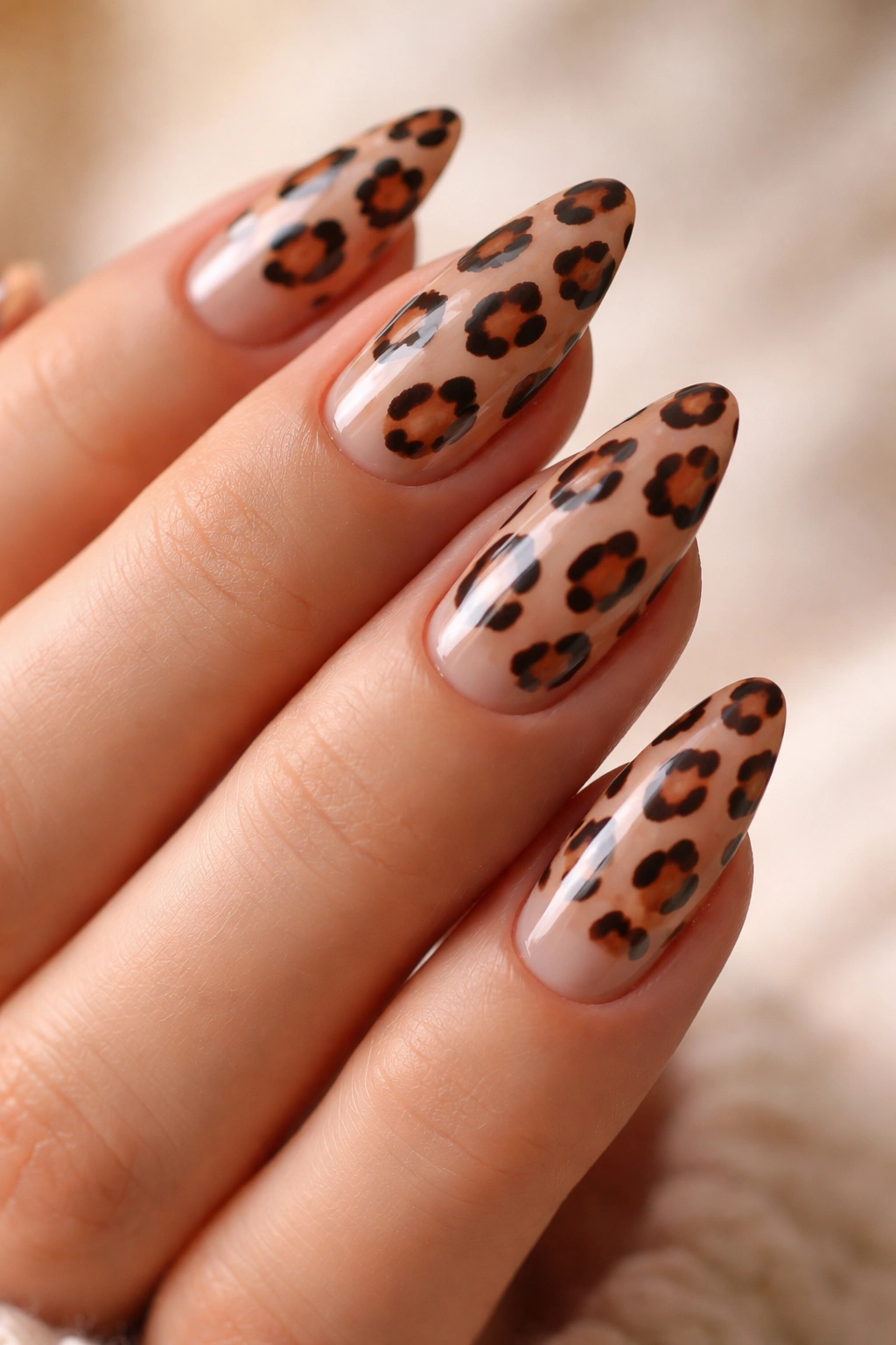 Close-up of almond nails with leopard print on a nude base, wearable leopard nails