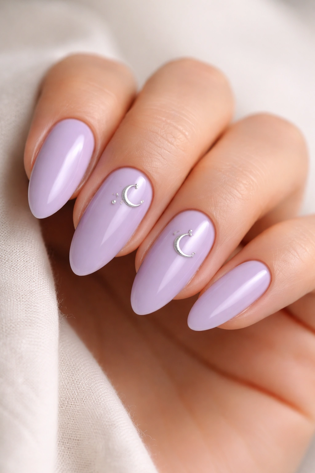 Almond nails with small silver moon phase motifs on lilac polish