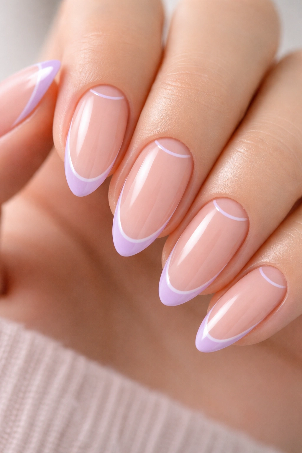Close-up of minimal lilac negative-space almond nails with a thin lilac edge on a nude base