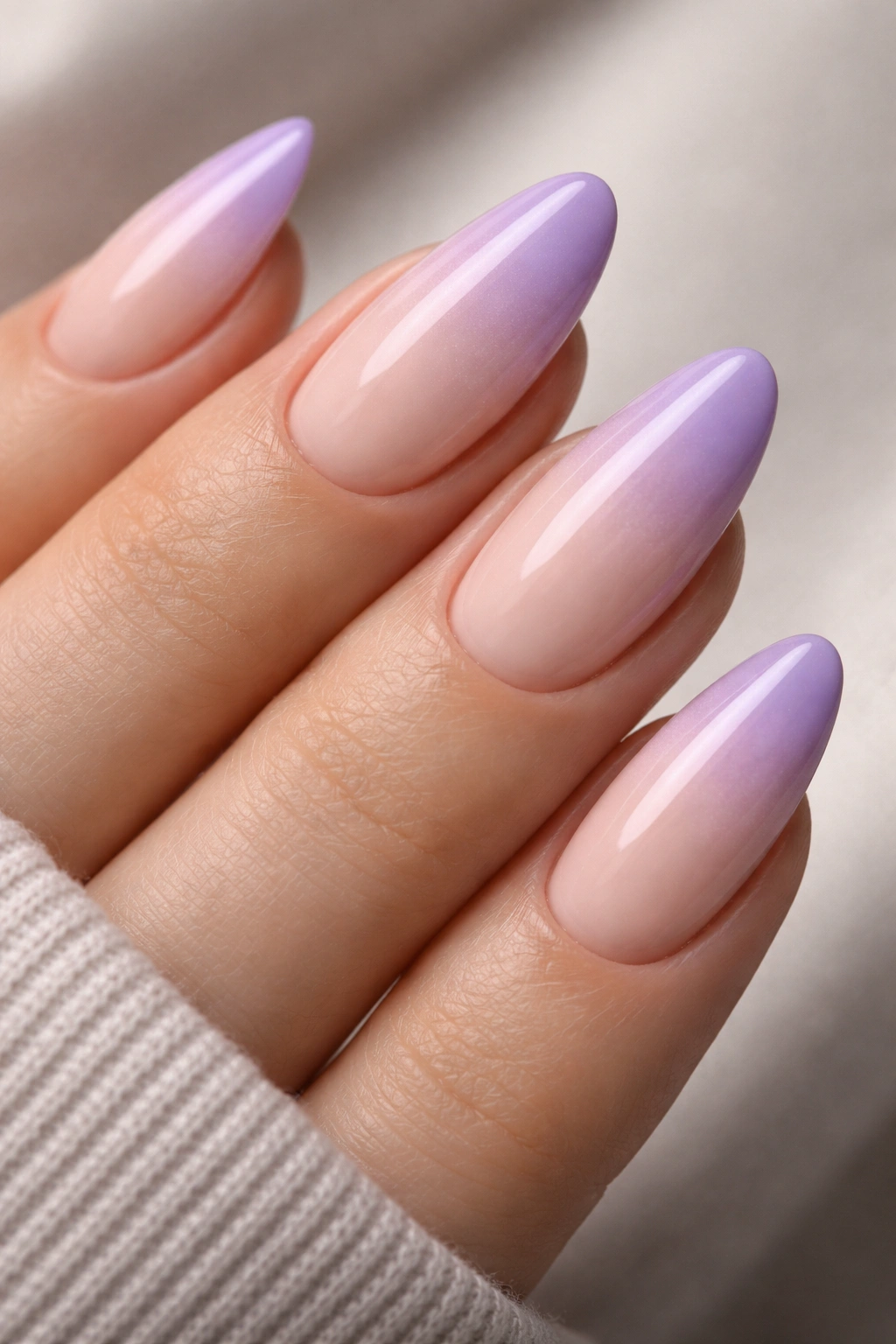 Close-up of almond nails with nude-to-lilac ombré on the tips