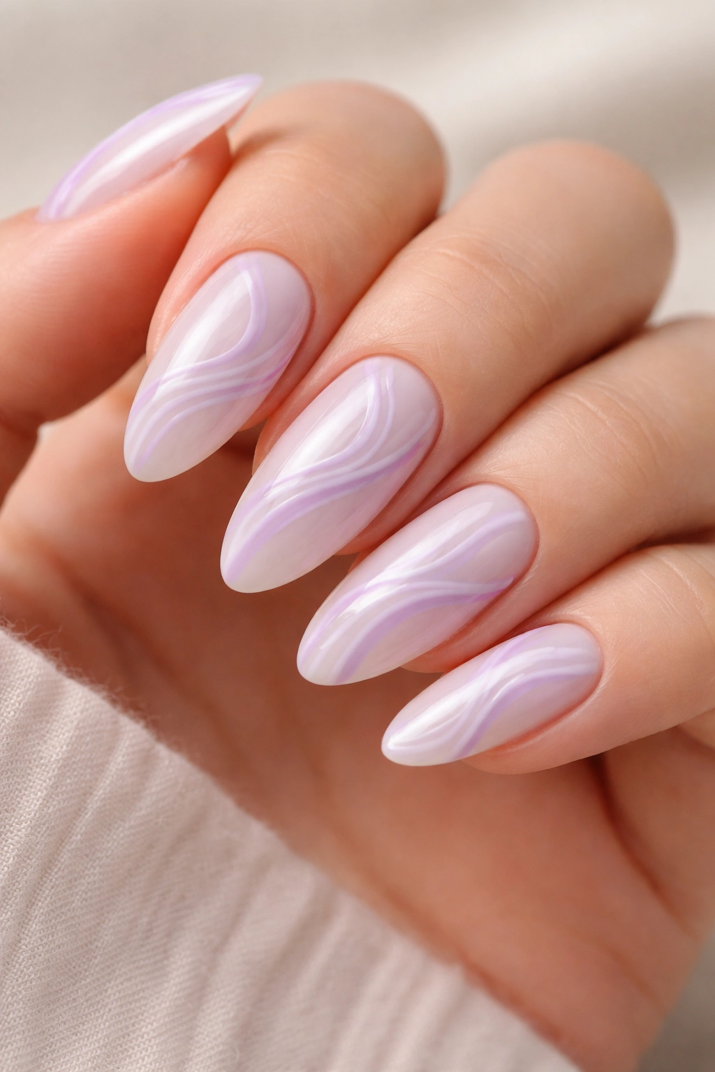 Close-up of lilac swirl nail art on milky almond nails