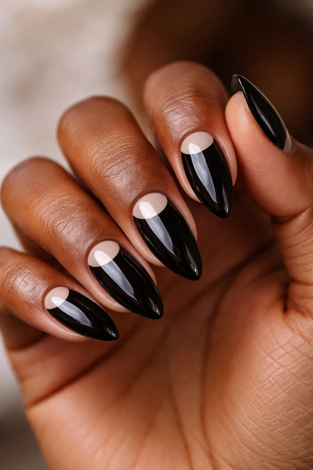 Close-up of black almond nails with nude half-moon at the base