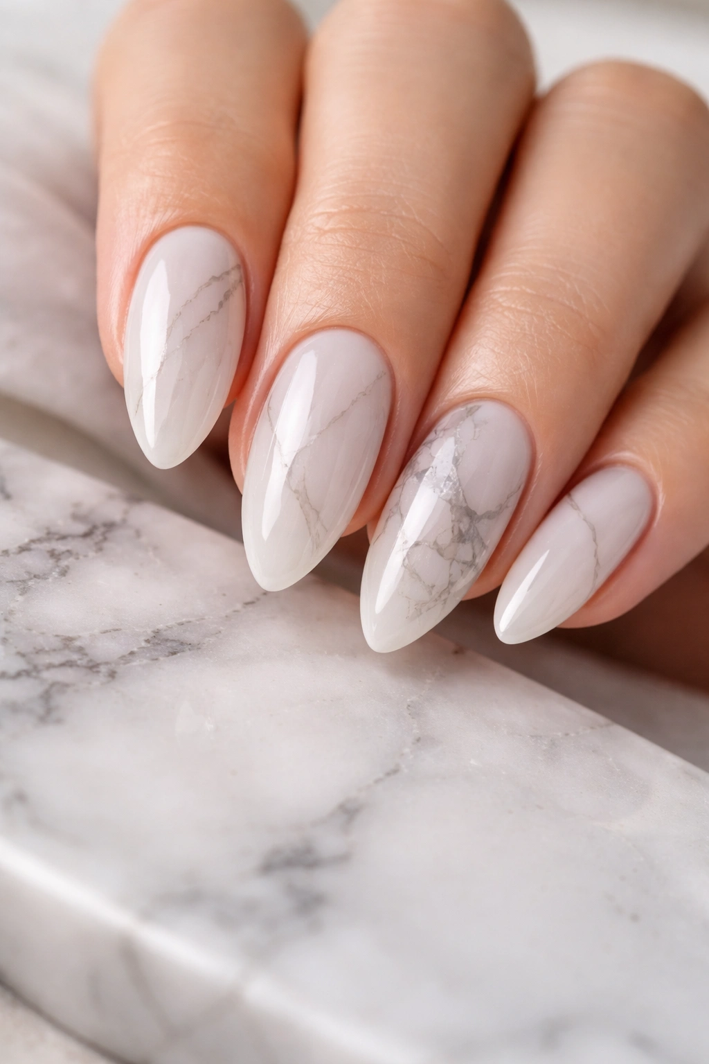 Close-up of marble almond nails with translucent base and subtle gray veins.