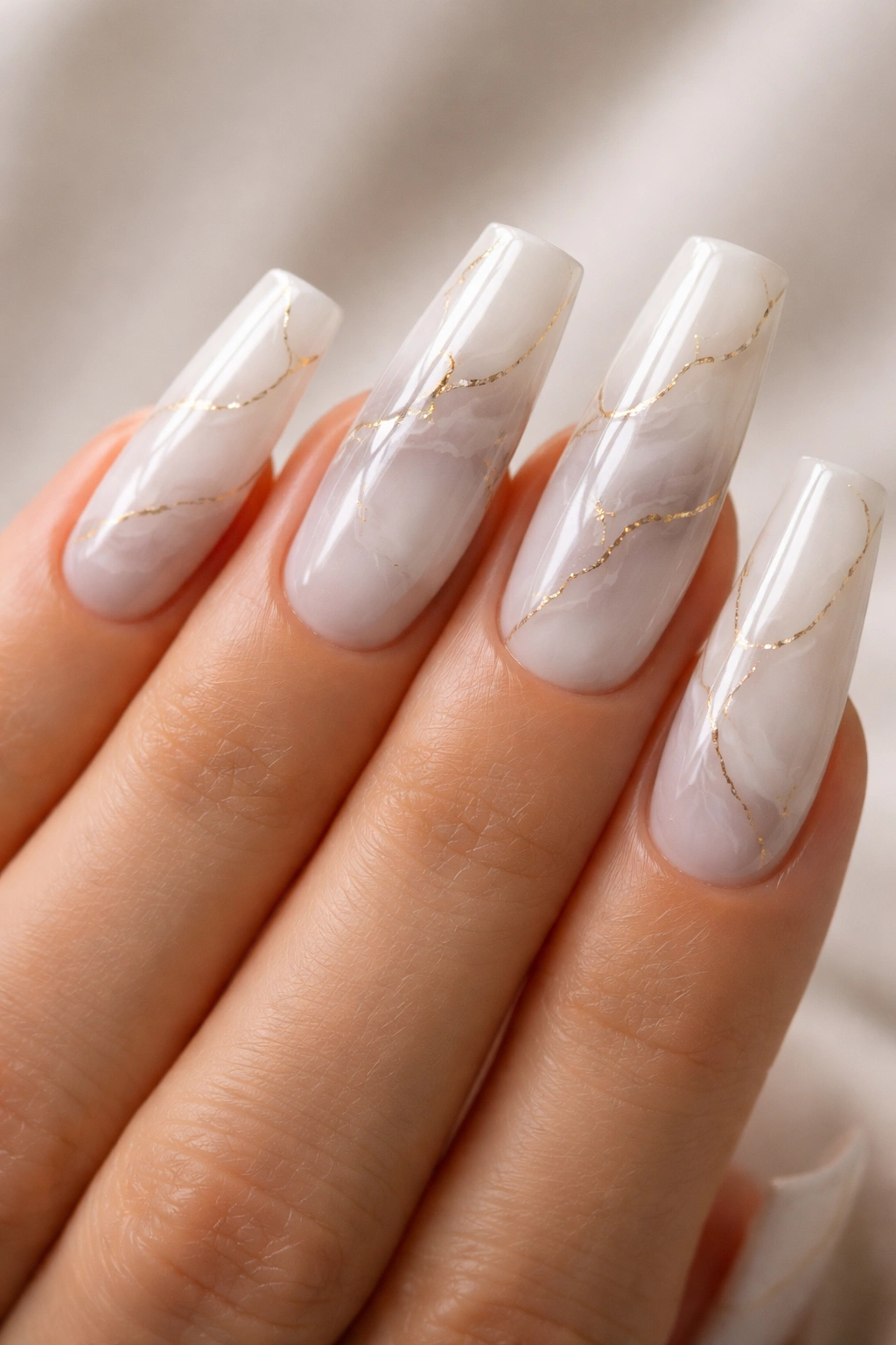 Close-up of soft marble white coffin nails with delicate gold veins