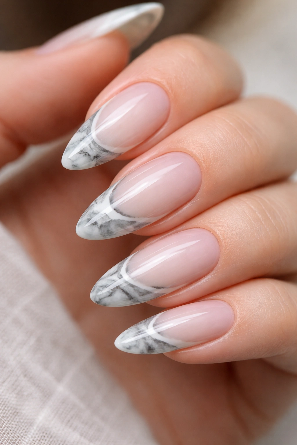Close-up of almond nails with marble tip patterns along the edge