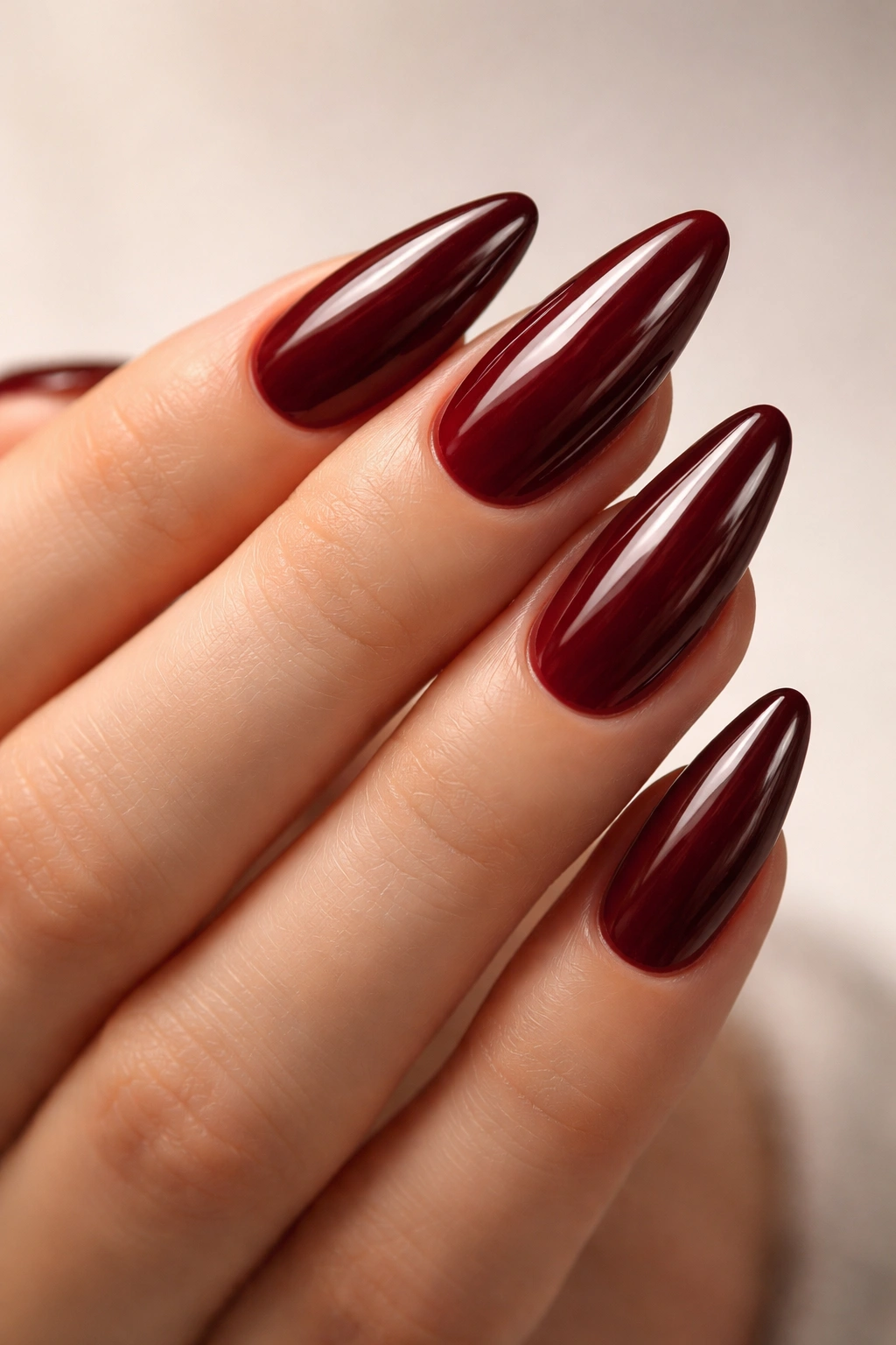 Almond nails with maroon glaze finish and glassy shine.