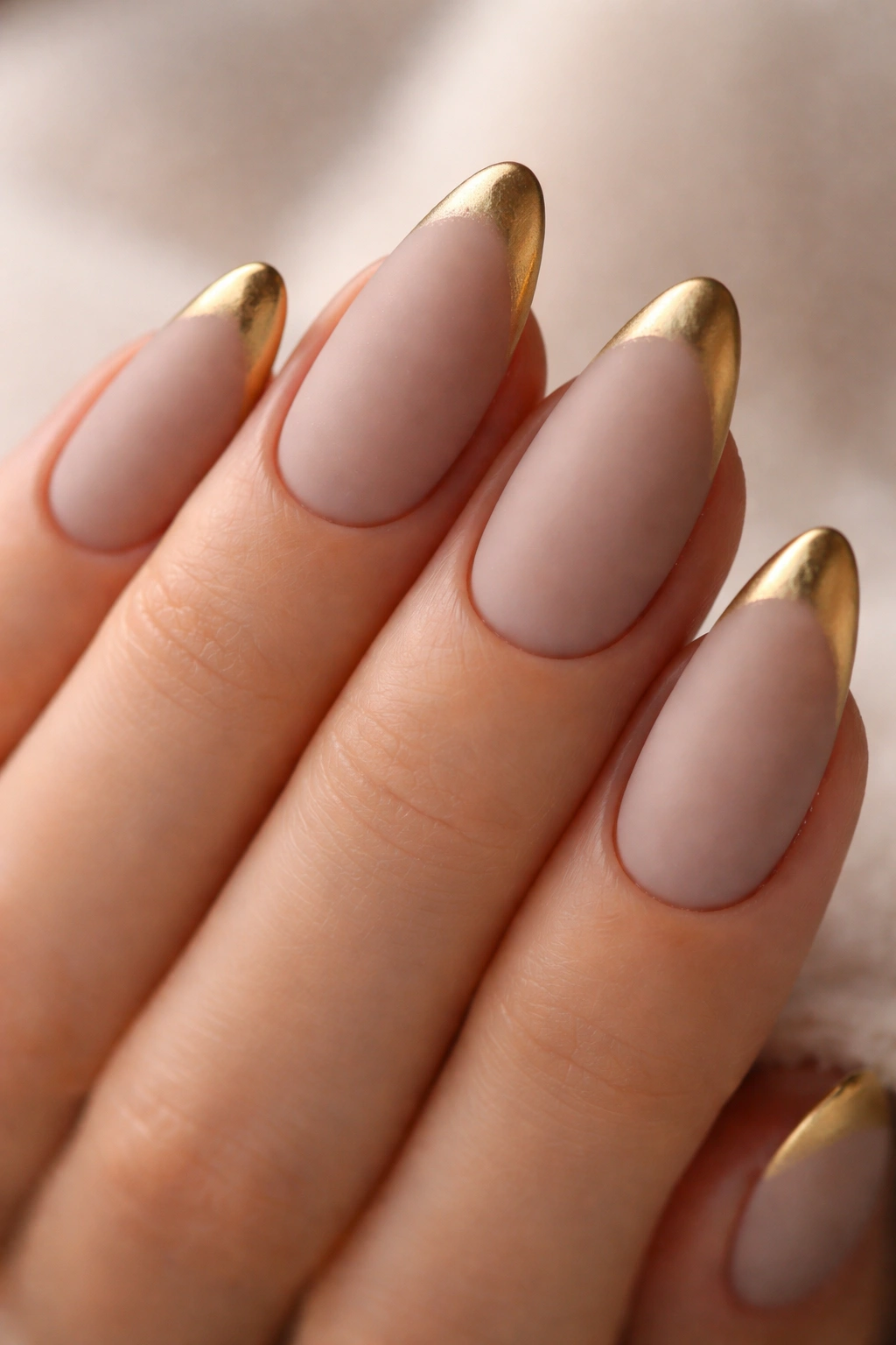 Close-up of matte almond nails with brushed gold tips