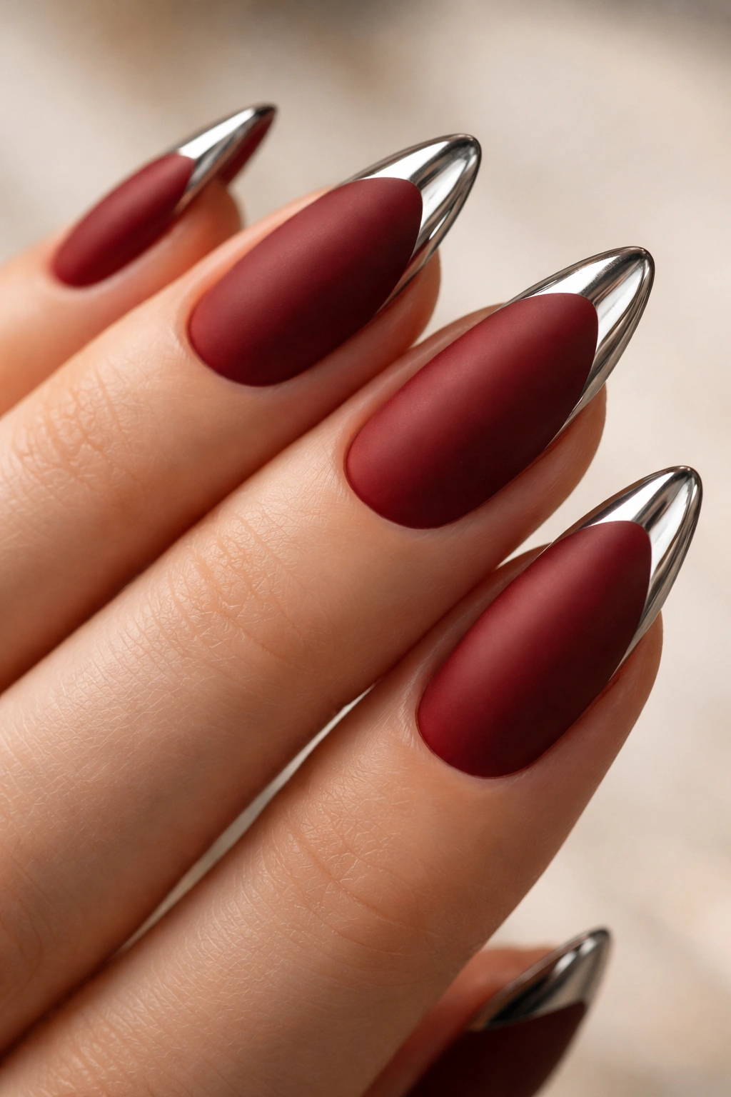 Almond nail with matte brick red base and chrome tip along edge