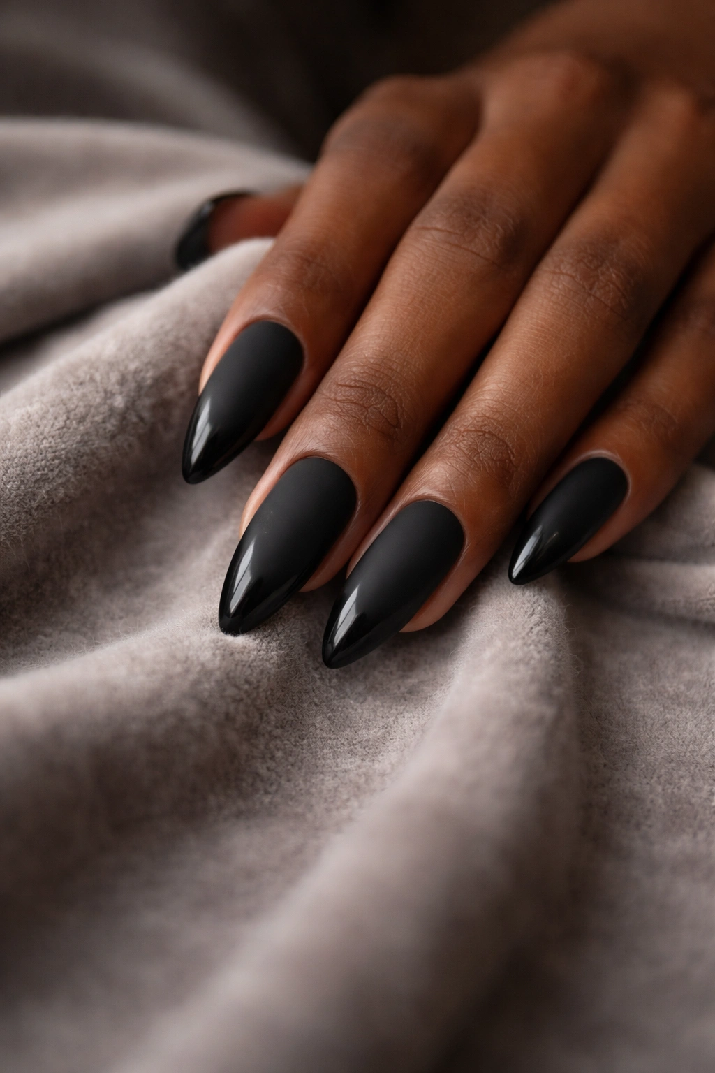 Close-up of matte black almond nails with glossy tips