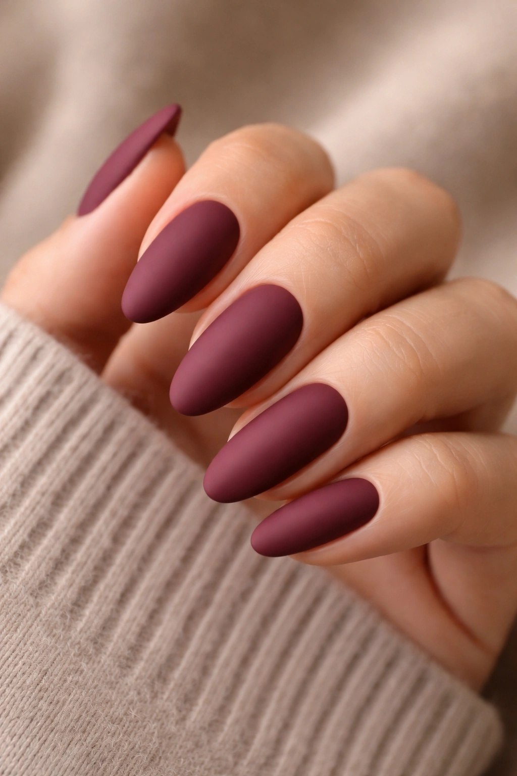 Close-up of matte burgundy almond nails with subtle texture