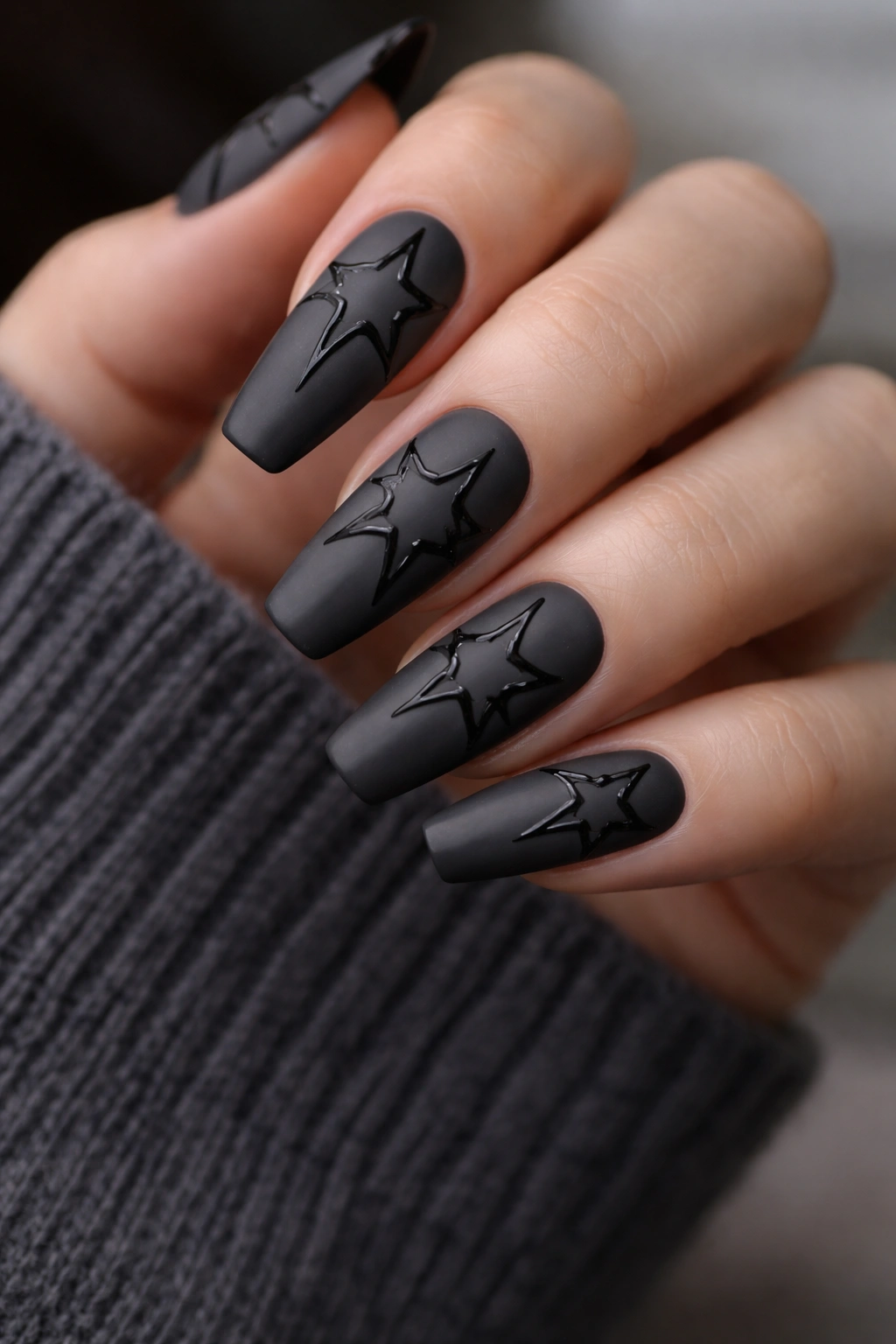 Close-up of matte charcoal coffin nails with glossy black star outlines