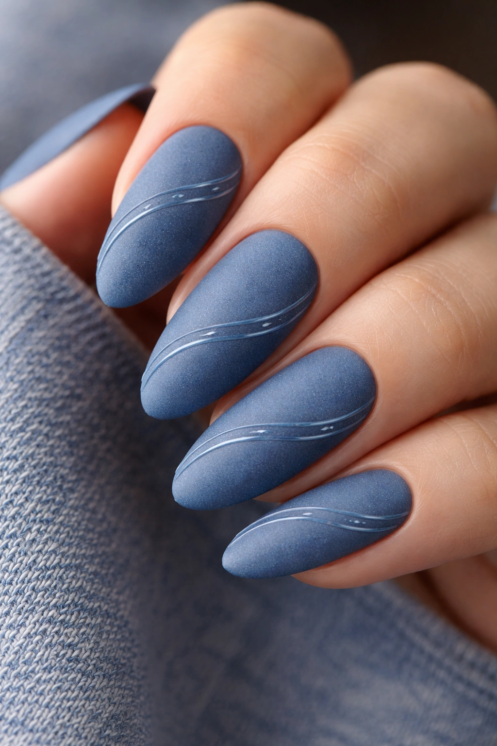 Matte denim blue almond nails with glossy wave lines