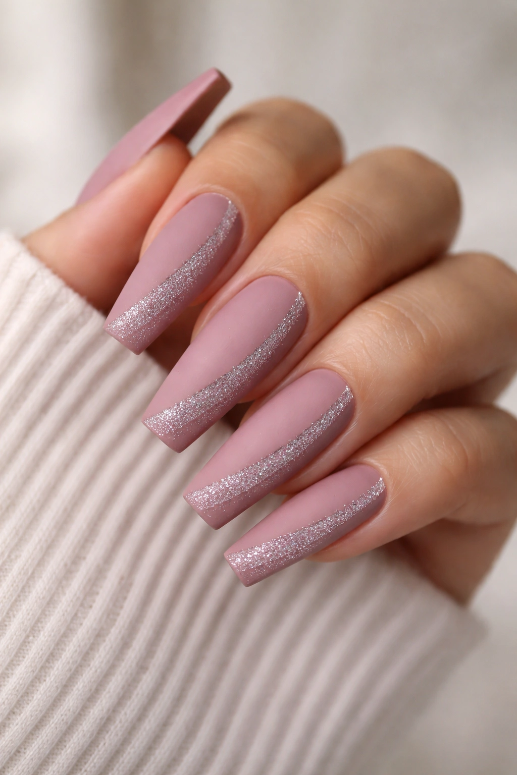 Close-up of dusty pink matte coffin nails with a thin diagonal glitter sweep along the side