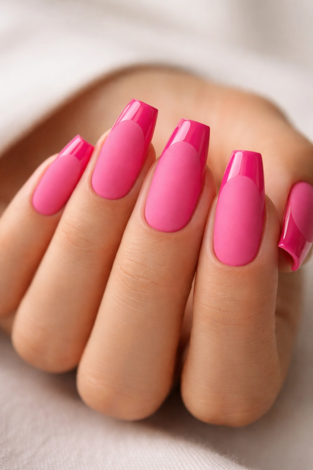 Coffin nails showing matte hot pink base with glossy pink tips against a neutral background