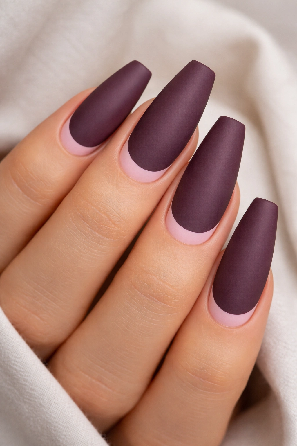 Matte plum coffin nails with a tiny pink moon near cuticle