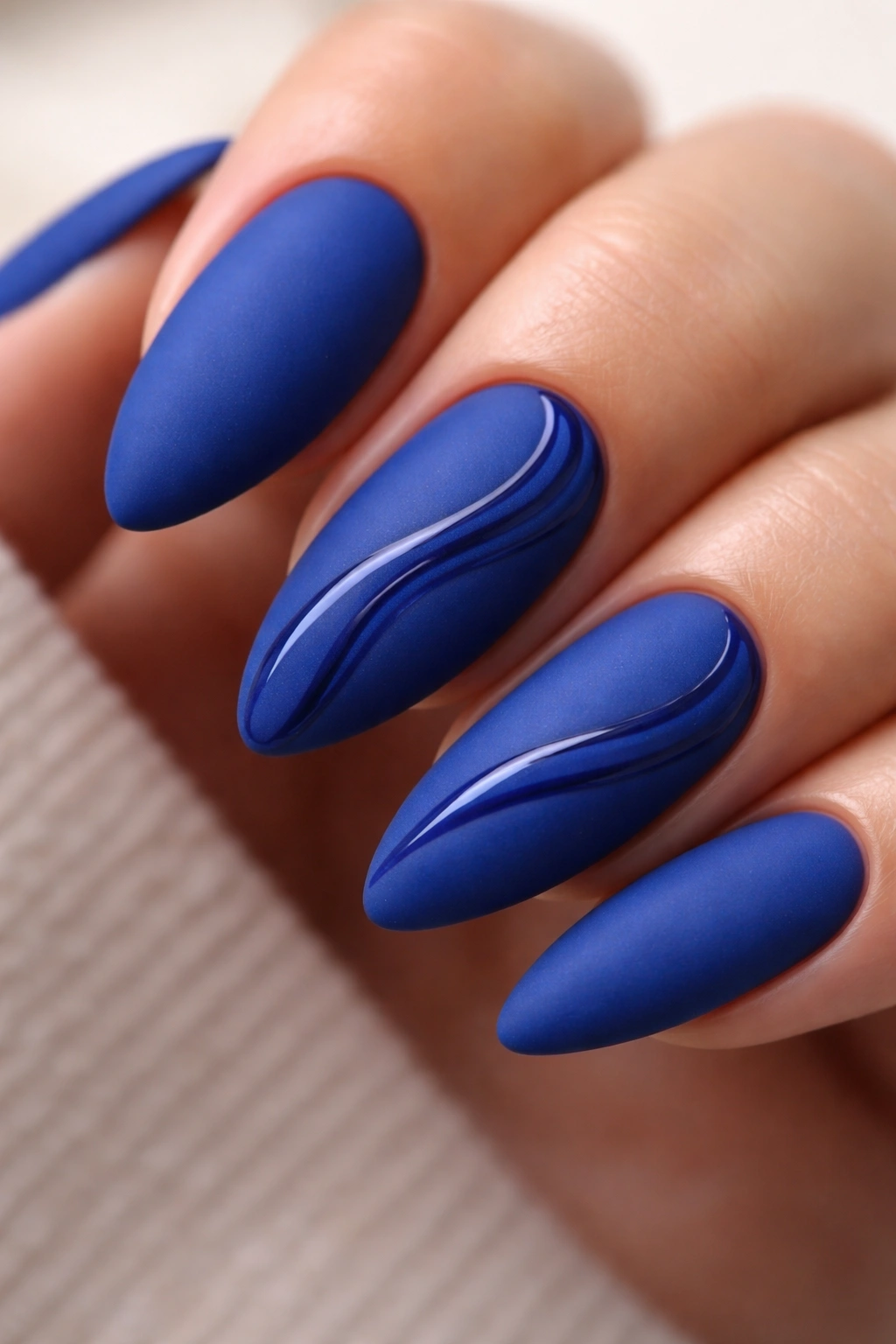 Almond nails in matte royal blue with glossy blue swirls
