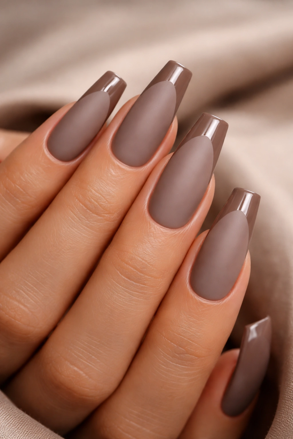 Close-up of long coffin nails with matte taupe base and glossy tips