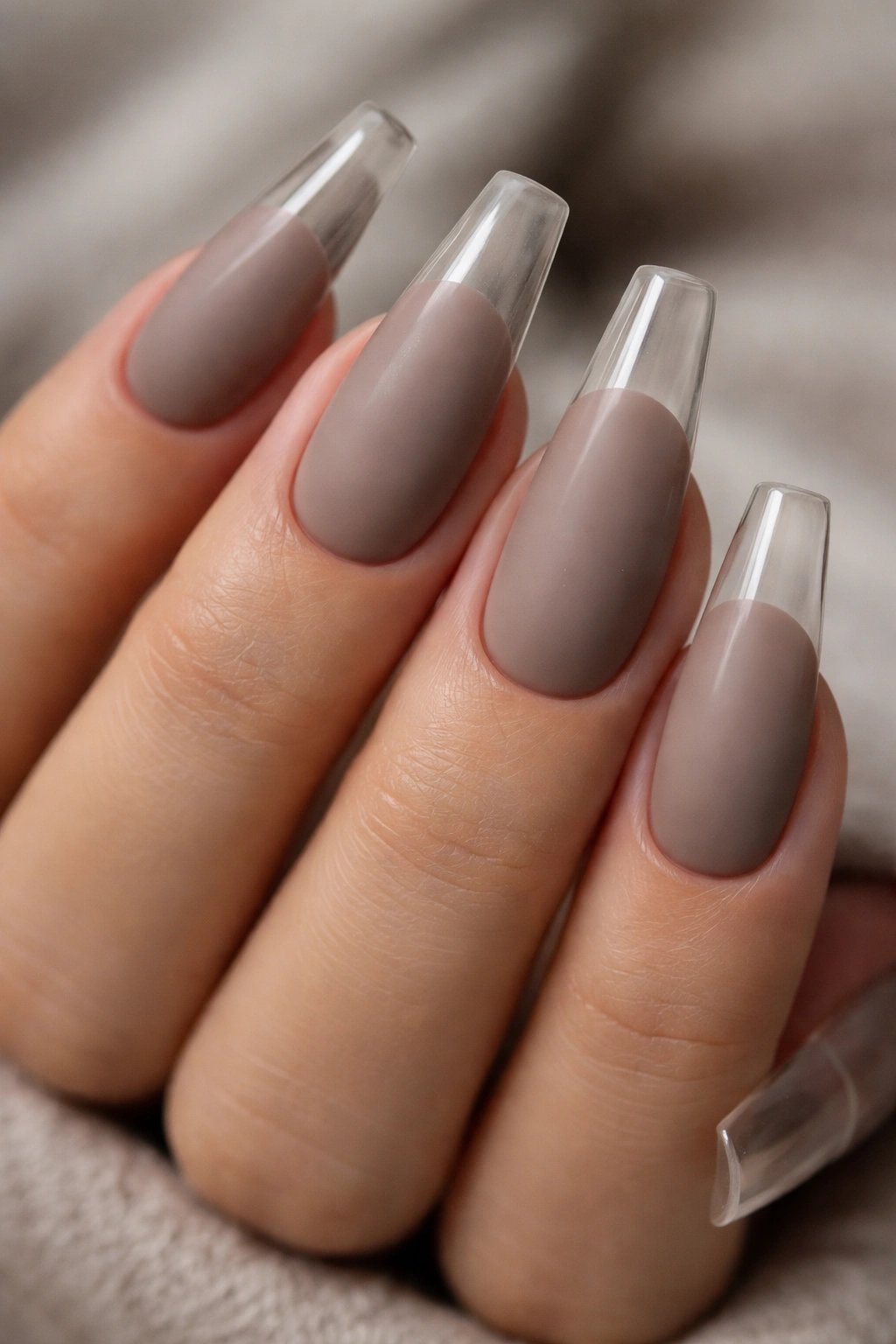 Close-up of long coffin nails with matte taupe base and glossy tips