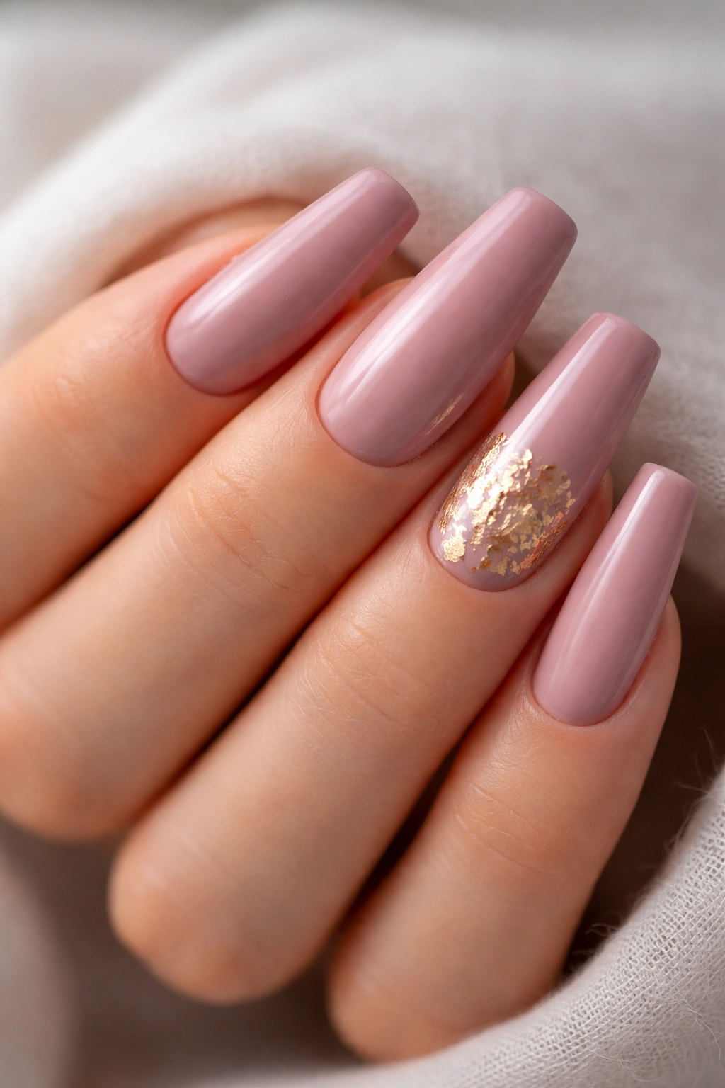 Close-up of mauve pink coffin nails with gold foil accents on select nails