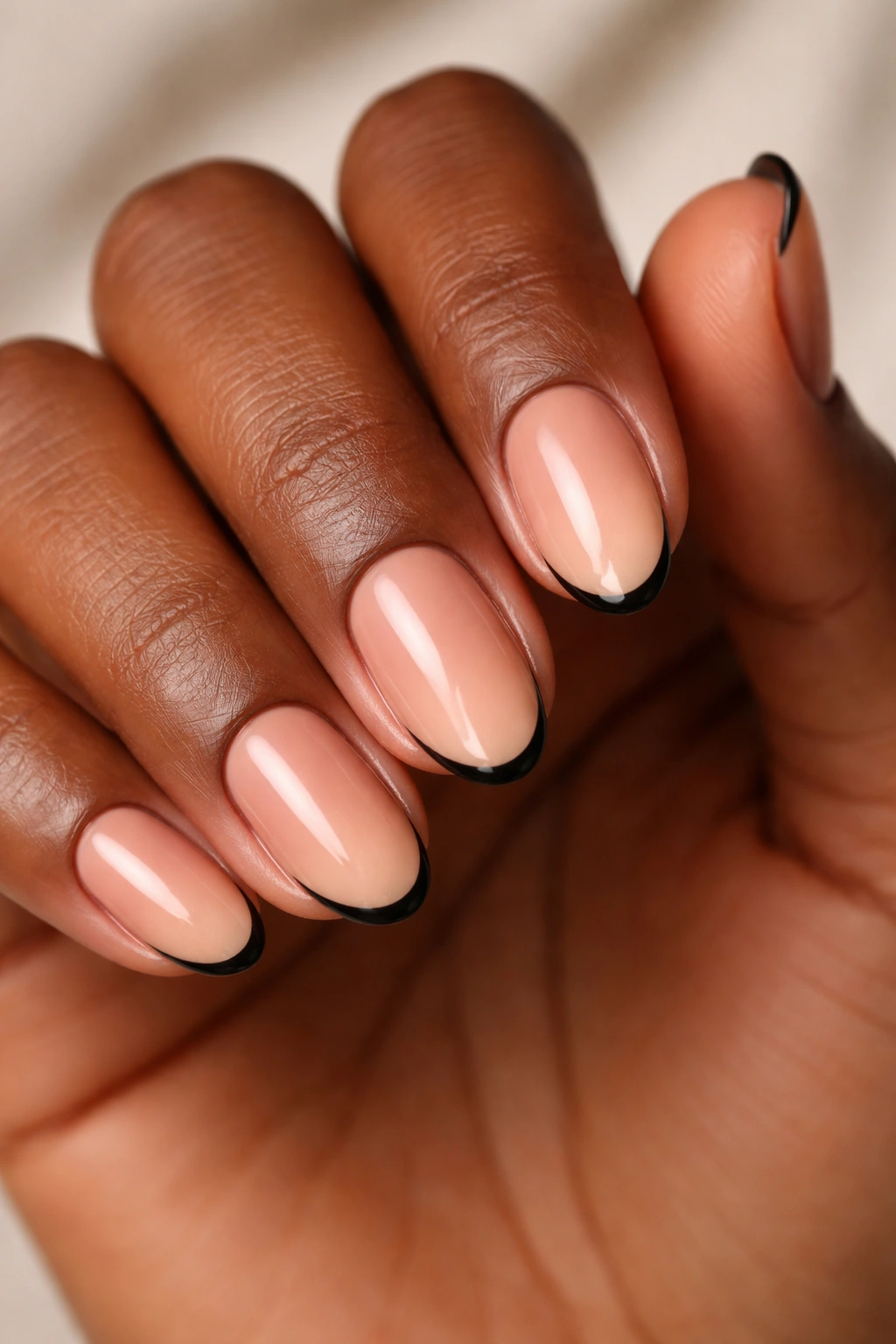 Close-up of almond nails on dark skin with tiny black tips