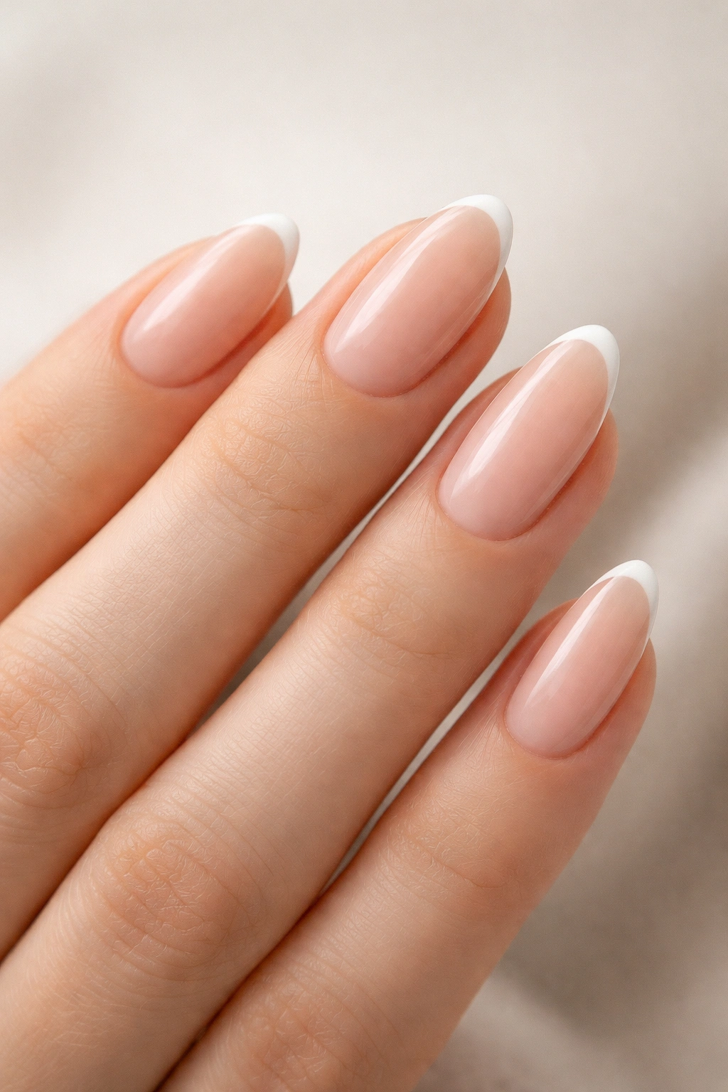 Close-up of almond nails with tiny micro French tips on nude base