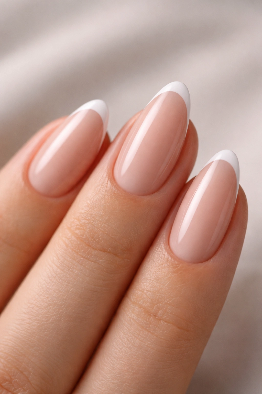 Close-up of almond nails with micro French tips on nude base
