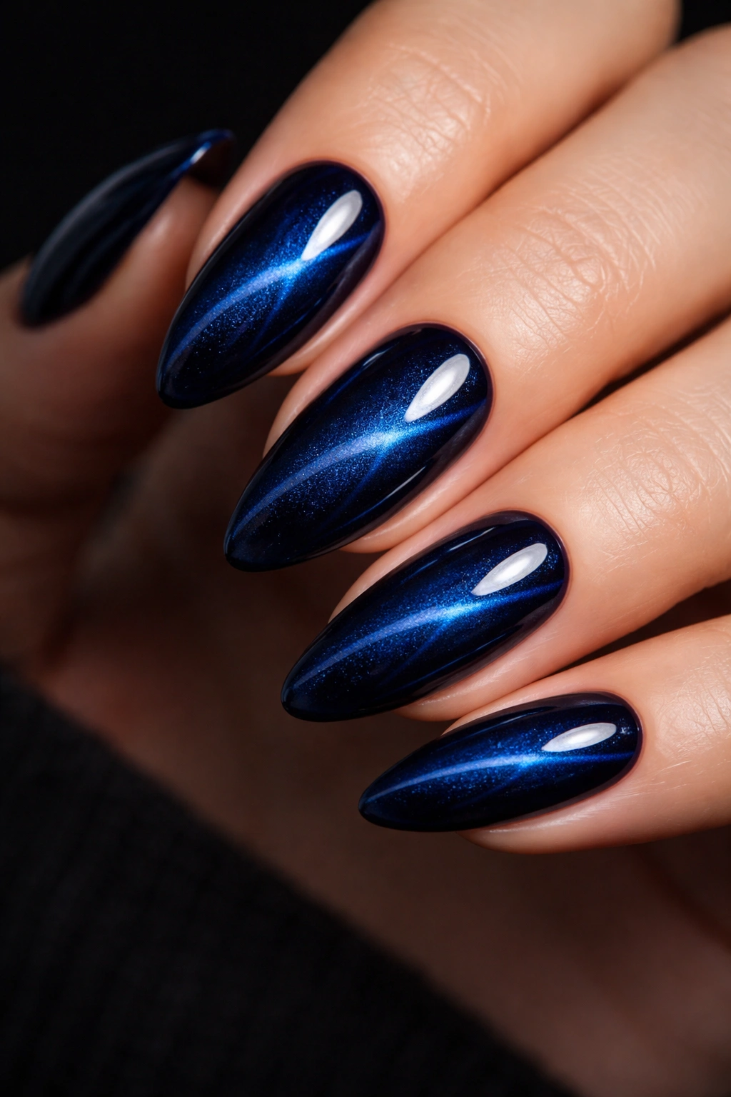 Macro shot of almond nails with midnight blue cat-eye effect