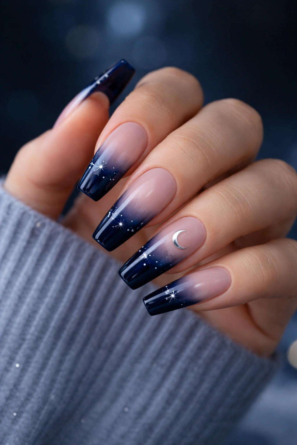 Close-up of coffin nails with midnight blue tips and tiny starbursts.