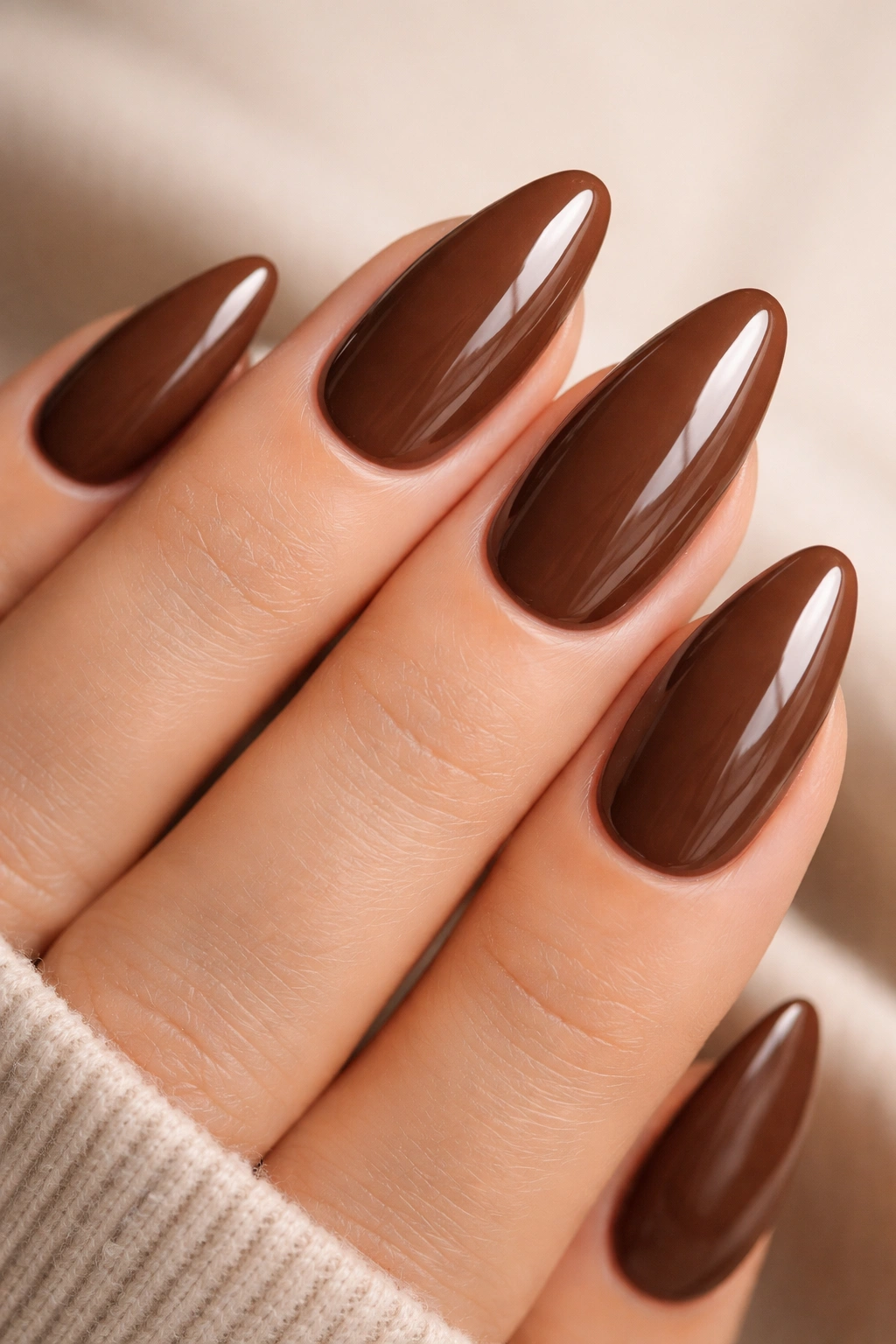 Close-up of glossy milk chocolate almond nails on a hand