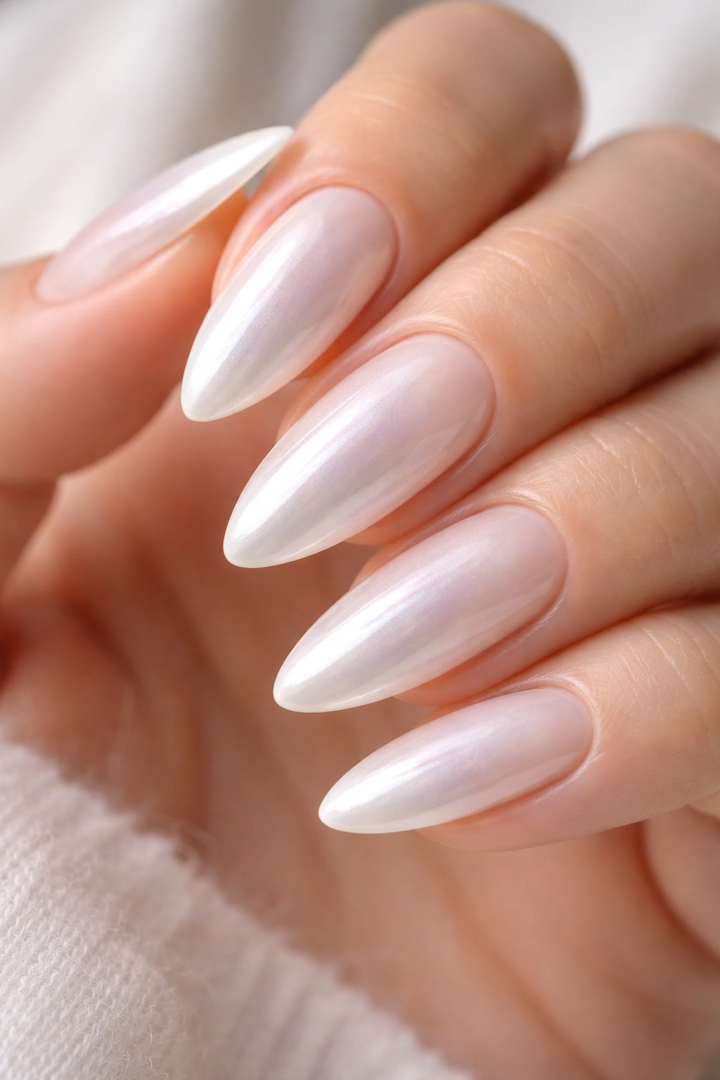 Close-up of almond nails with sheer milky white chrome and pearl-like finish