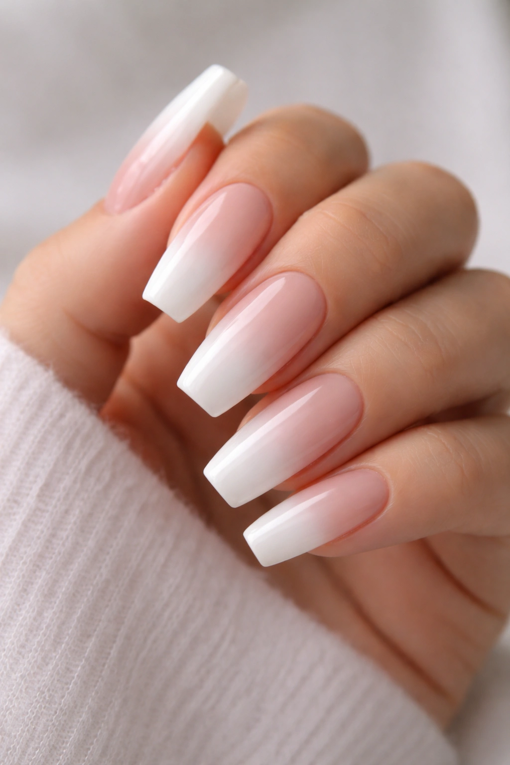 Close-up of baby boomer milky fade coffin nails with nude base and white tips