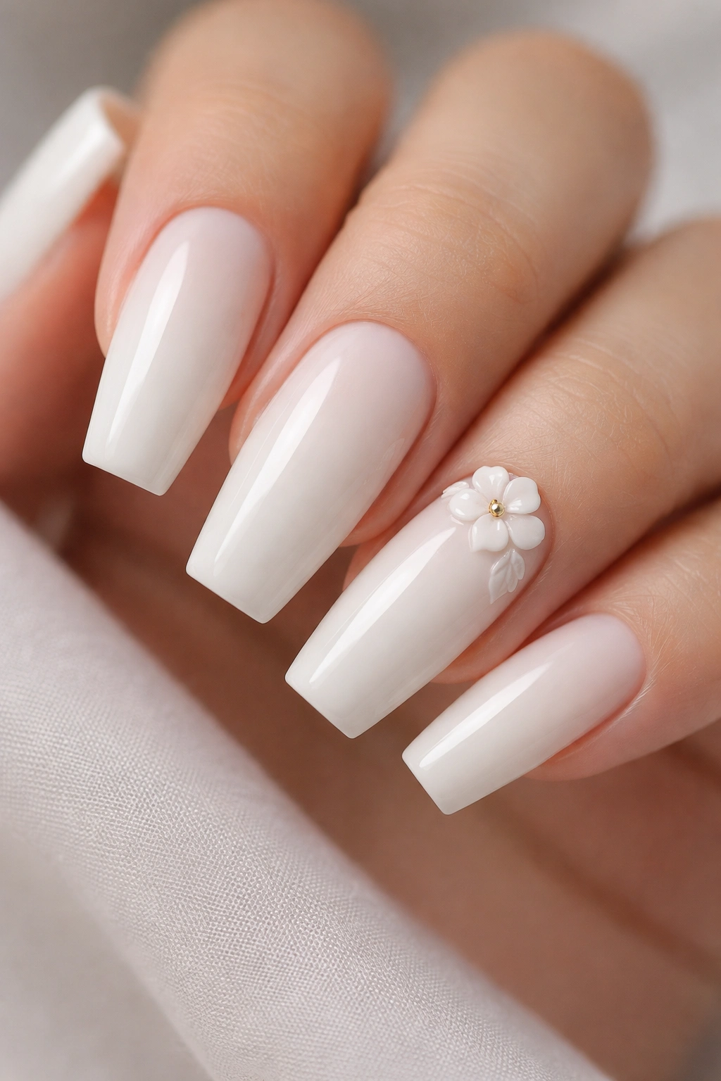 Milky white coffin nail with a small 3D floral accent on ring finger