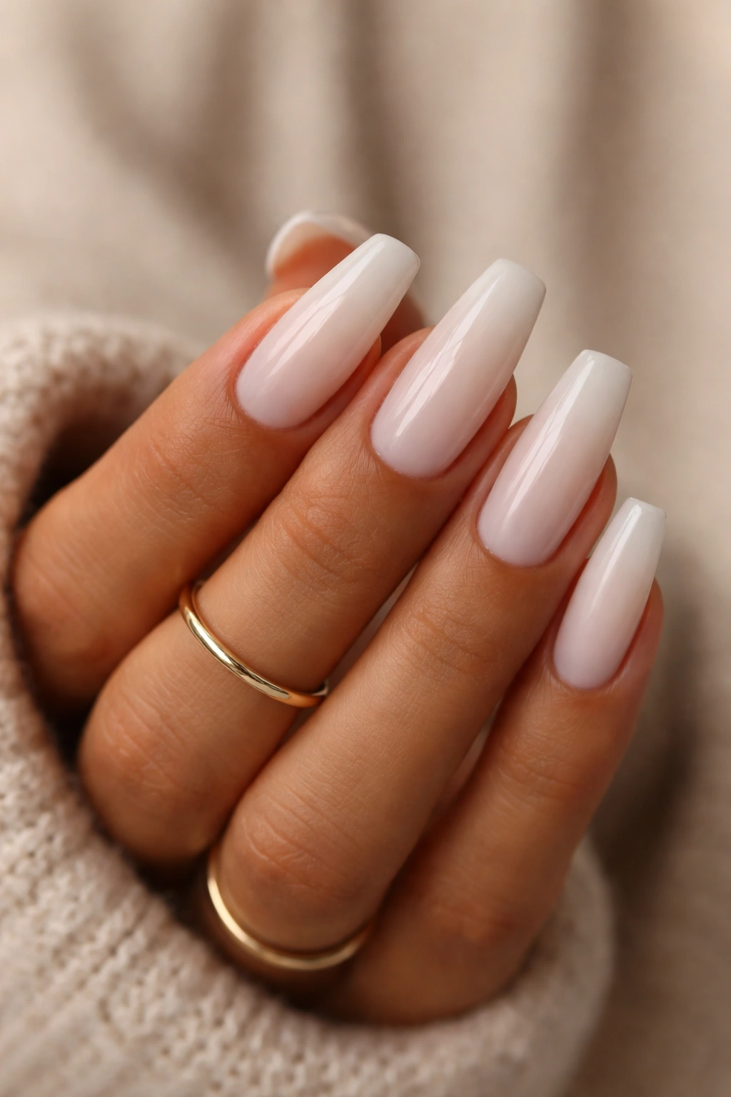 Hand with milky white coffin nails matching warm skin tone and gold ring