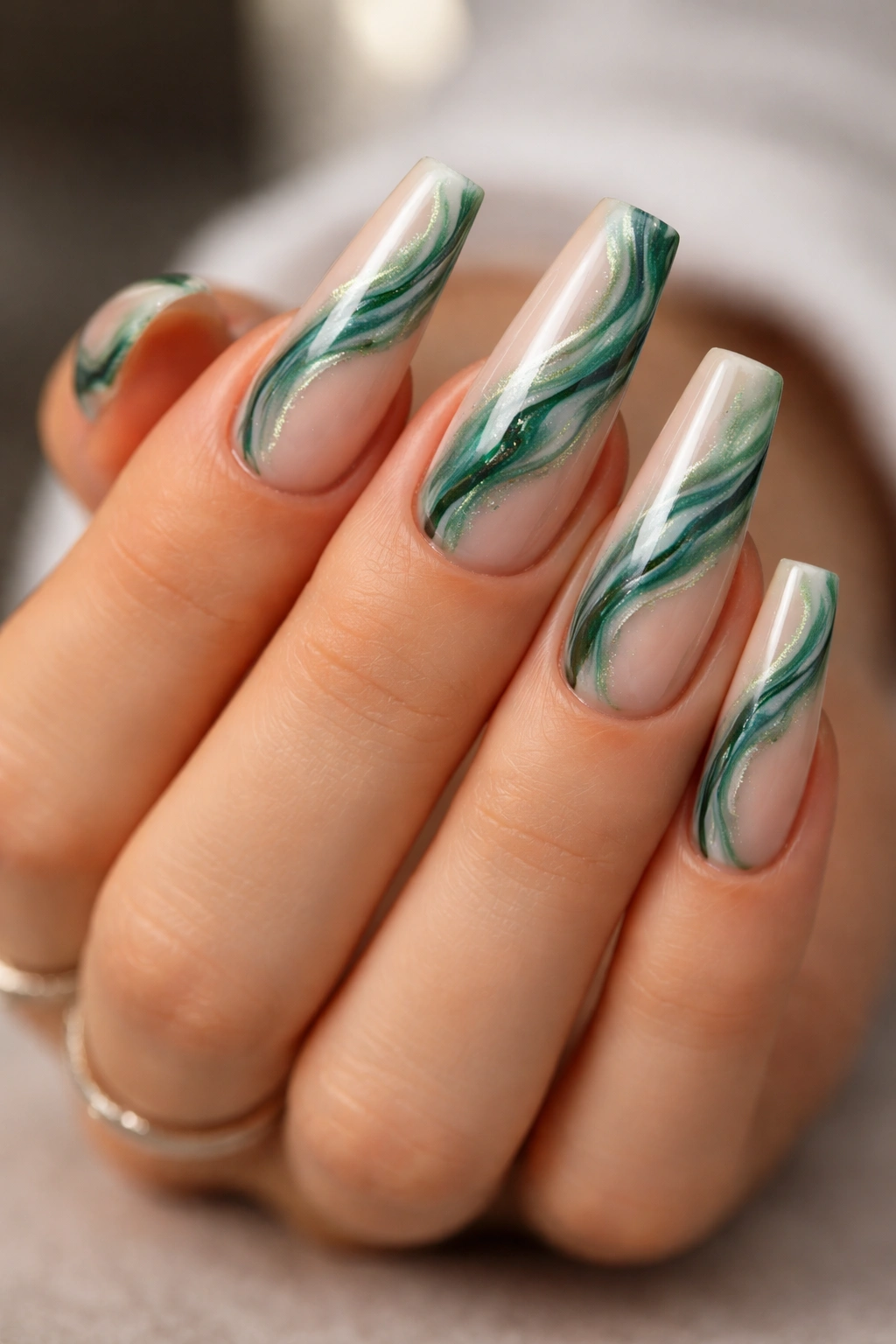 Close-up of Milky Nude Emerald Marble Coffin Nails with green swirls