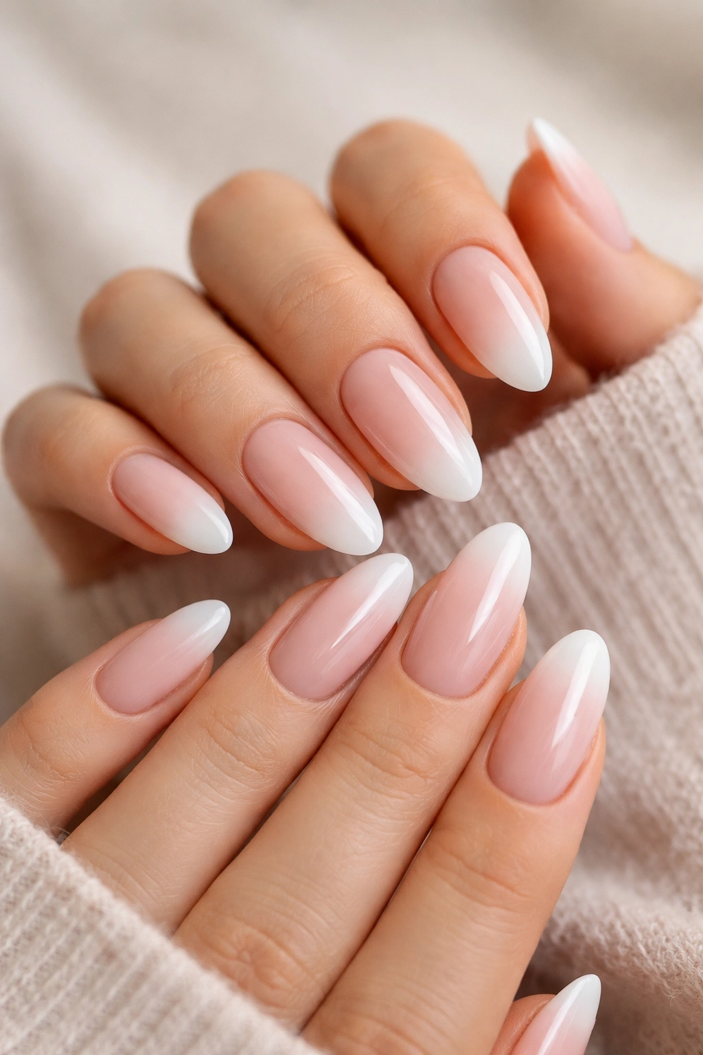 Close-up of milky pink ombre almond nails with sheer pink base and white tip