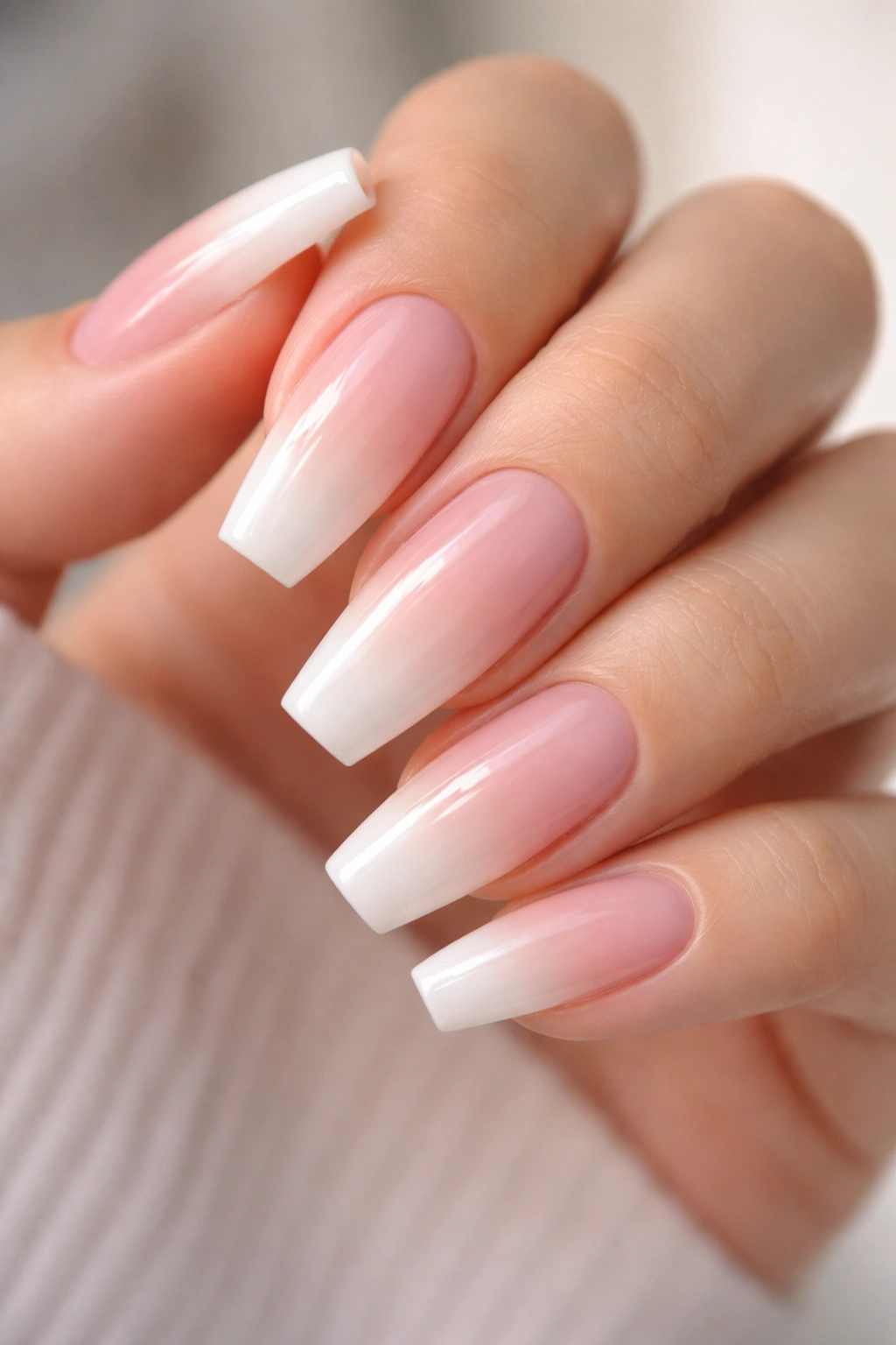 Medium coffin nails with milky tip gradient on a hand
